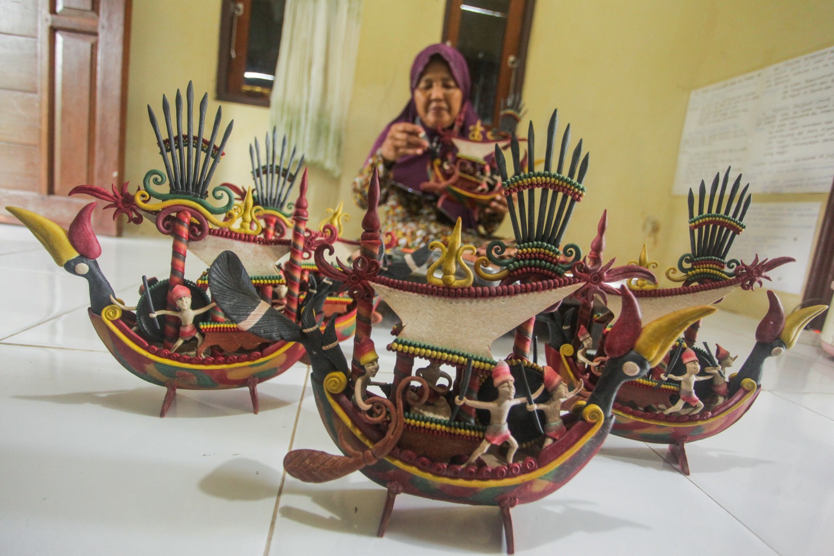 Perajin getah nyatu menyelesaikan pesanan miniatur kapal dengan motif Dayak Kalteng di rumahnya di Palangkaraya, Kalteng.