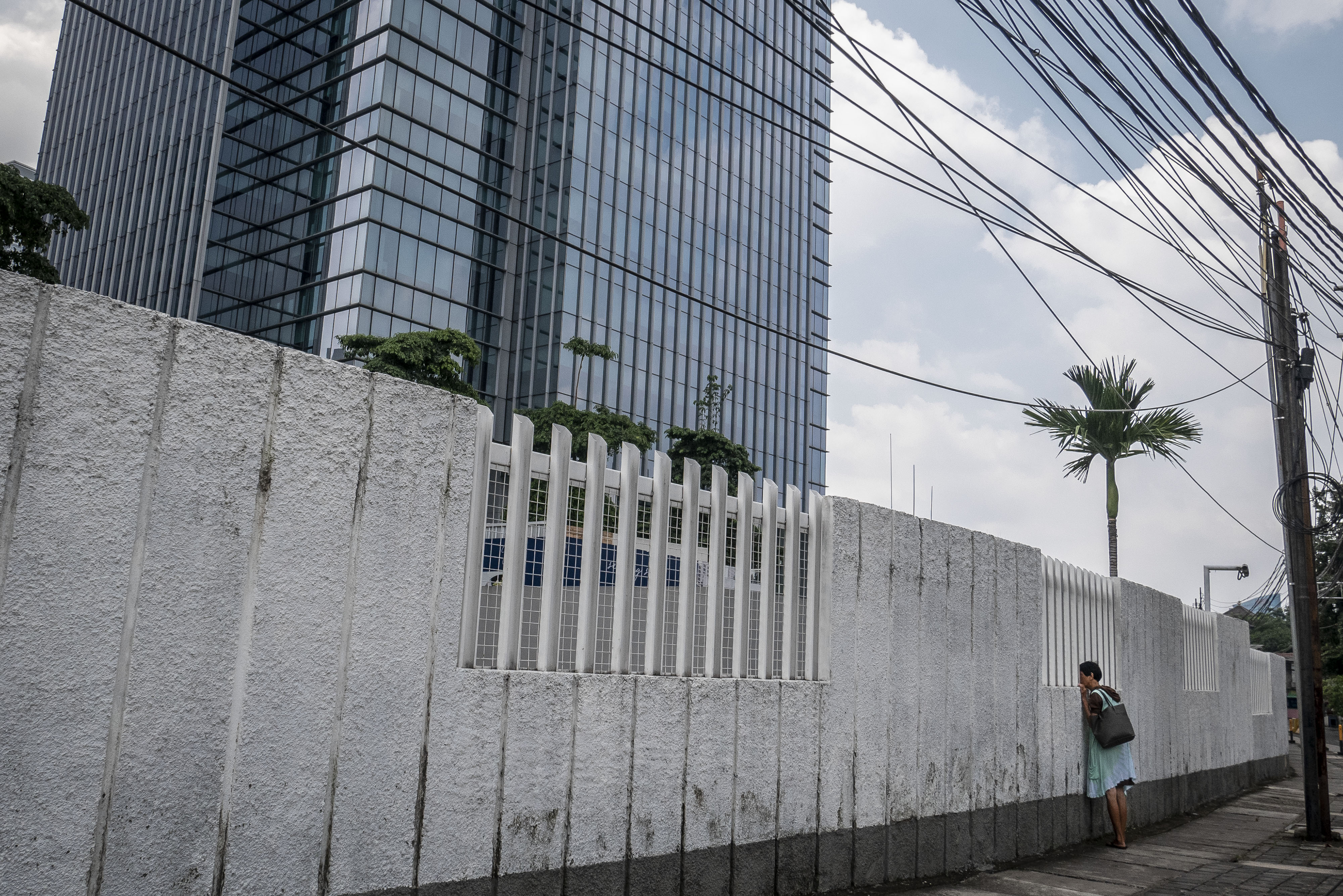 Pejalan kaki melihat gedung perkantoran dari sela-sela pagar di kawasan Kuningan, Jakarta