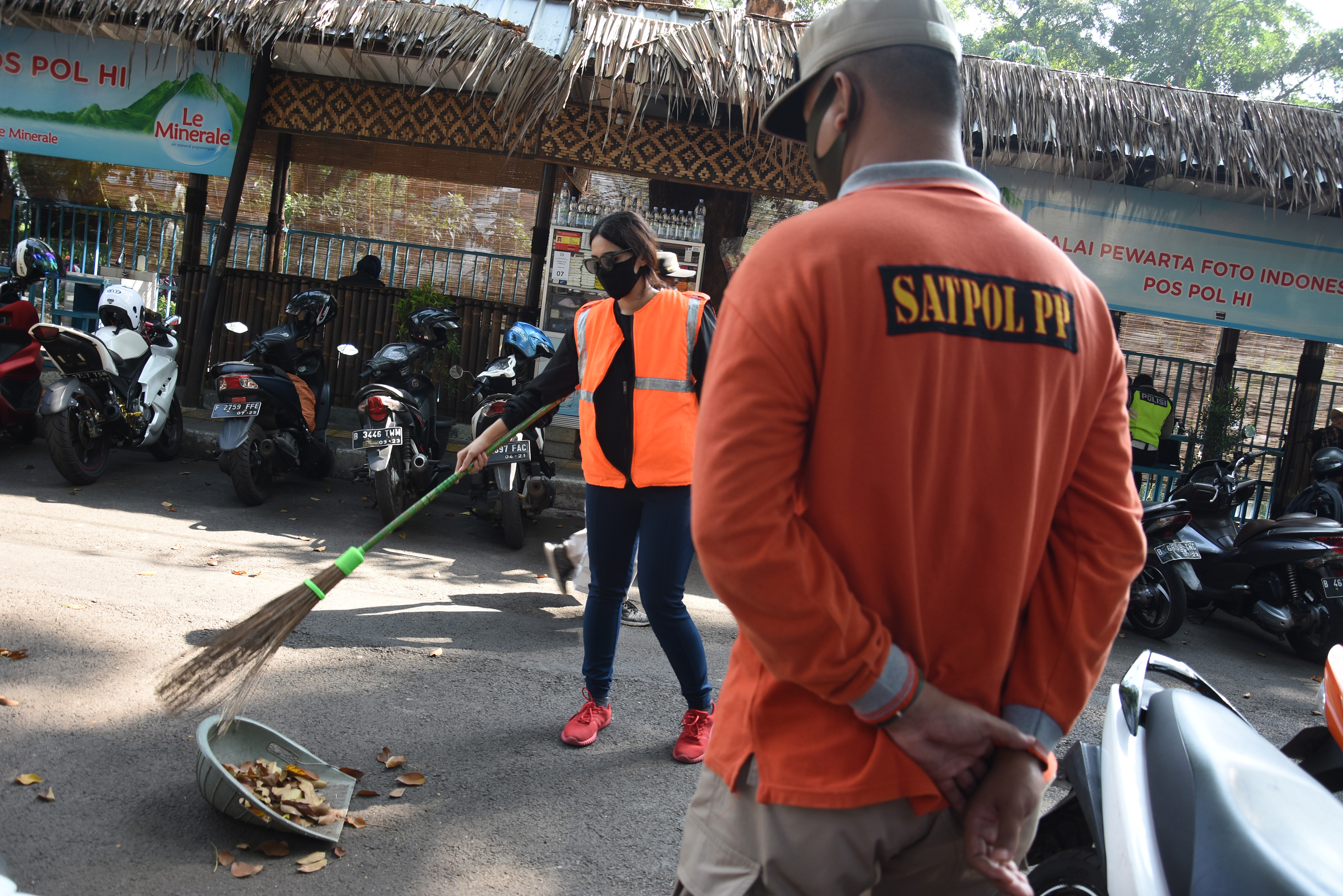 Pelanggar protokol kesehatan mendapatkan sanksi kerja sosial menyapu jalan di kawasan Bundaran HI, Jakarta, Minggu (26/7/2020).
