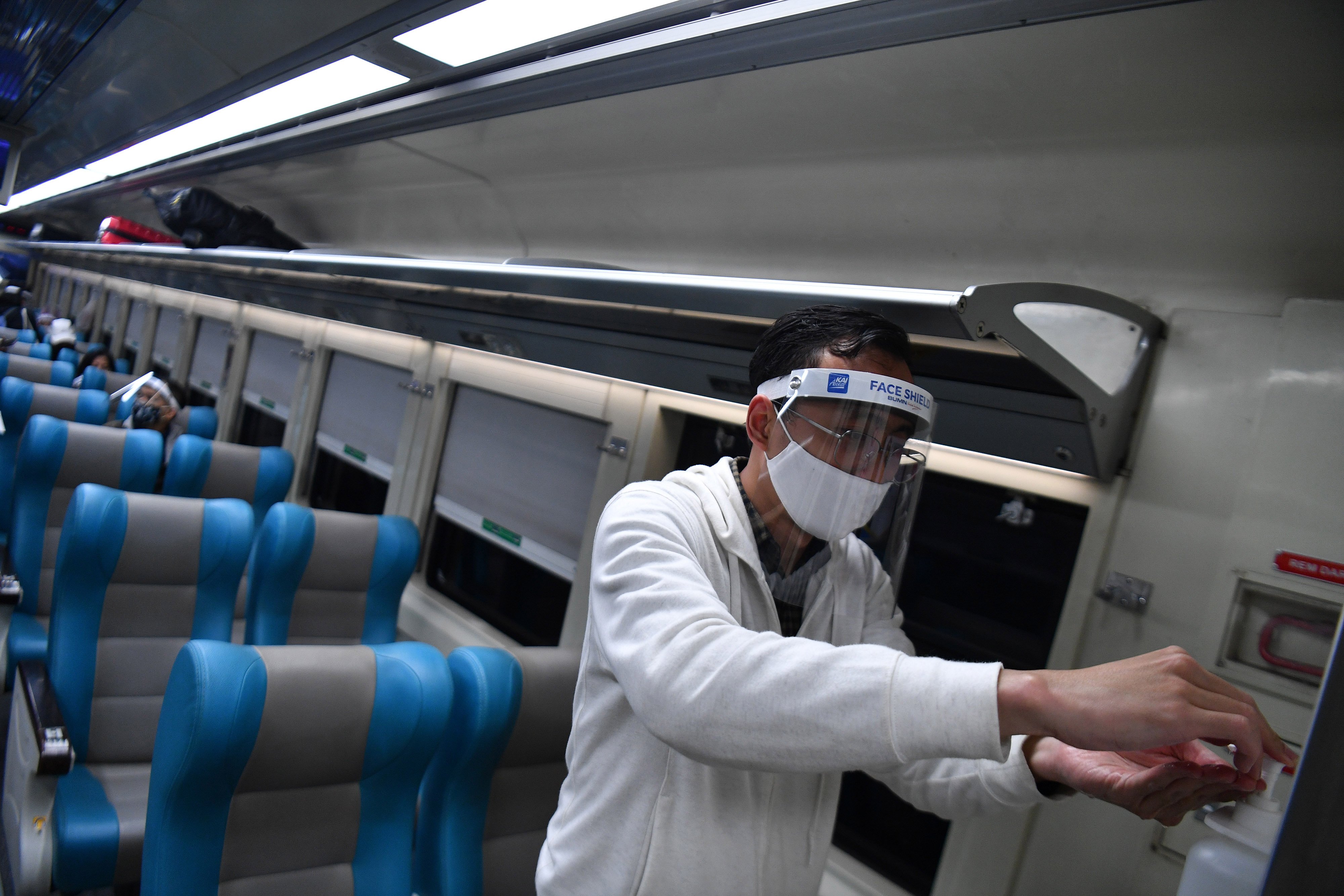 Penumpang kereta api jarak jauh menggunakan cairan pembersih tangan.