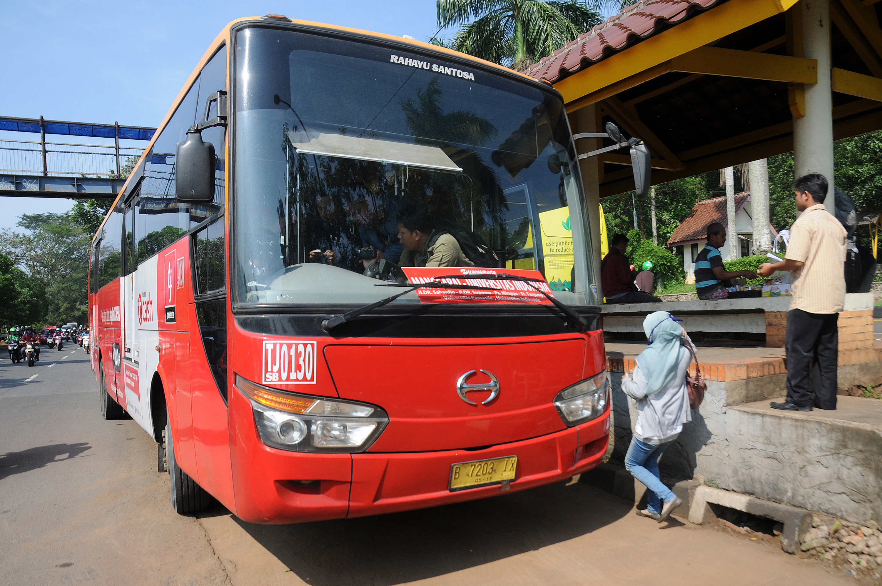 Bus Trans-Jakarta mengangkut penumpang di Halte UI.