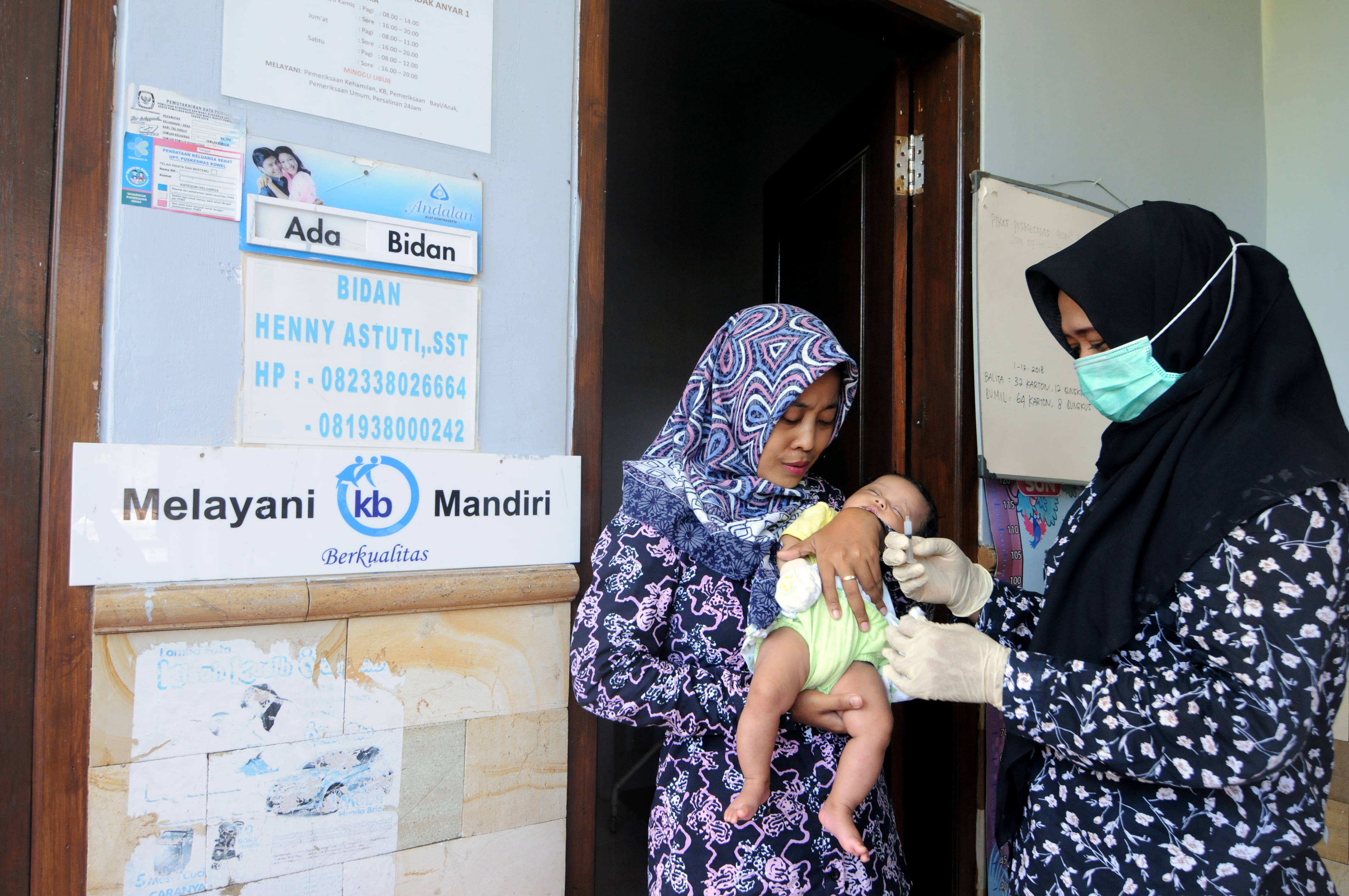 Seorang bidan (kanan) menyuntikkan imunisasi pada bayi usia dua bulan di Pamekasan, Jawa Timur, untuk mencegah stunting.