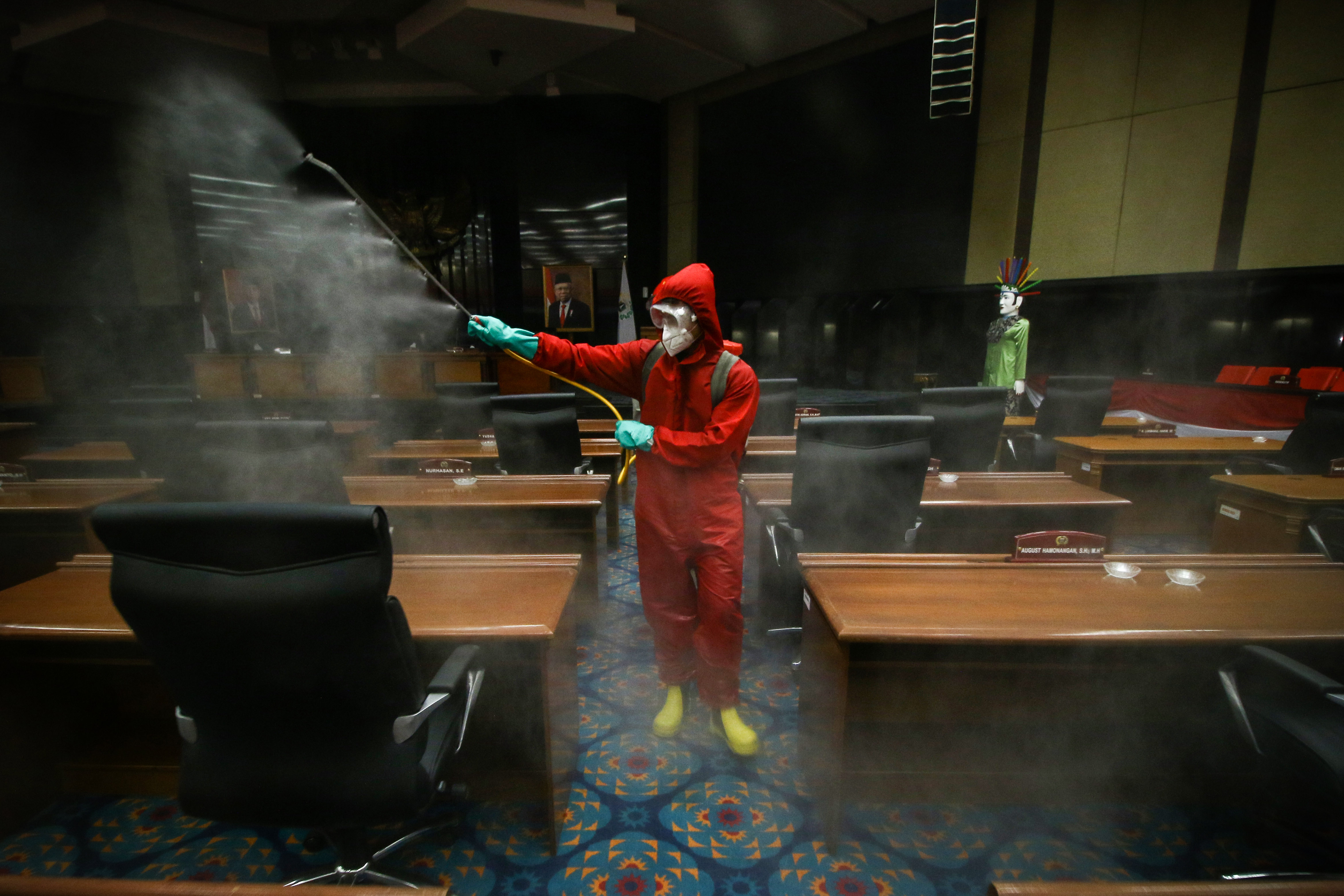 Petugas menyemprotkan cairan disinfektan di ruang sidang paripurna DPRD DKI Jakarta, Rabu (29/7/2020)