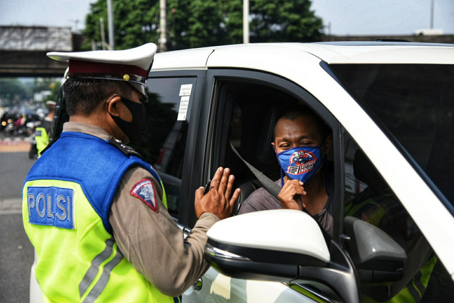 Polisi memberhentikan kendaraan bermotor saat diberlakukannya kembali ganjil-genap
