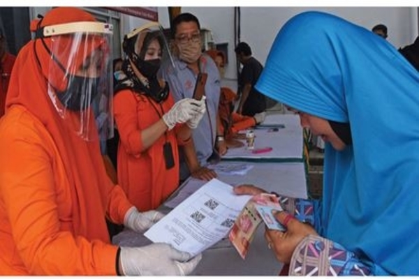 Petugas Kantor Pos menyerahkan bukti verifi kasi pemberian bantuan sosial tunai kepada warga penerima manfaat di Kantor Pos Serang, Banten, 