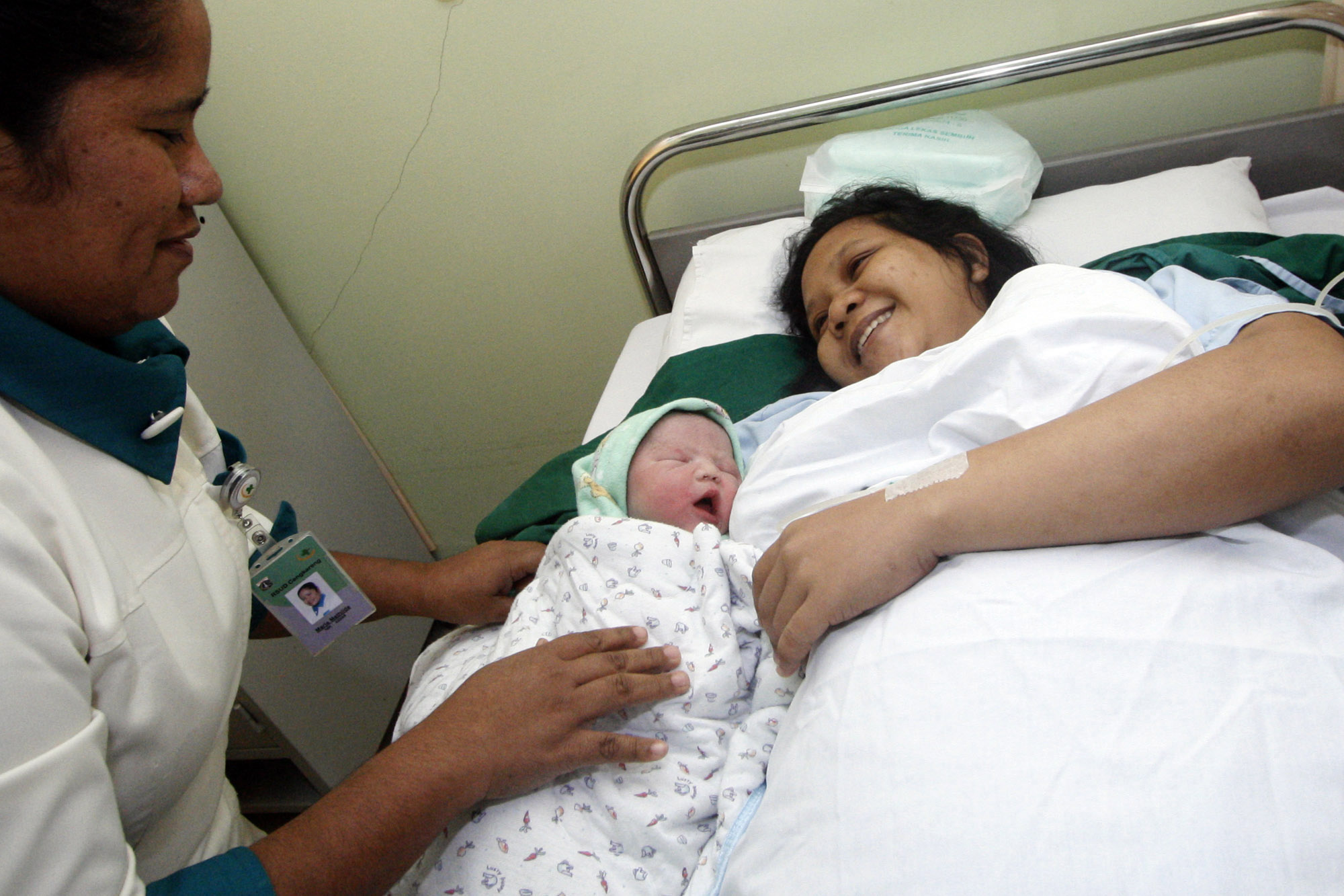 Perawat memberikan bayi  yang baru lahir kepada ibunya.