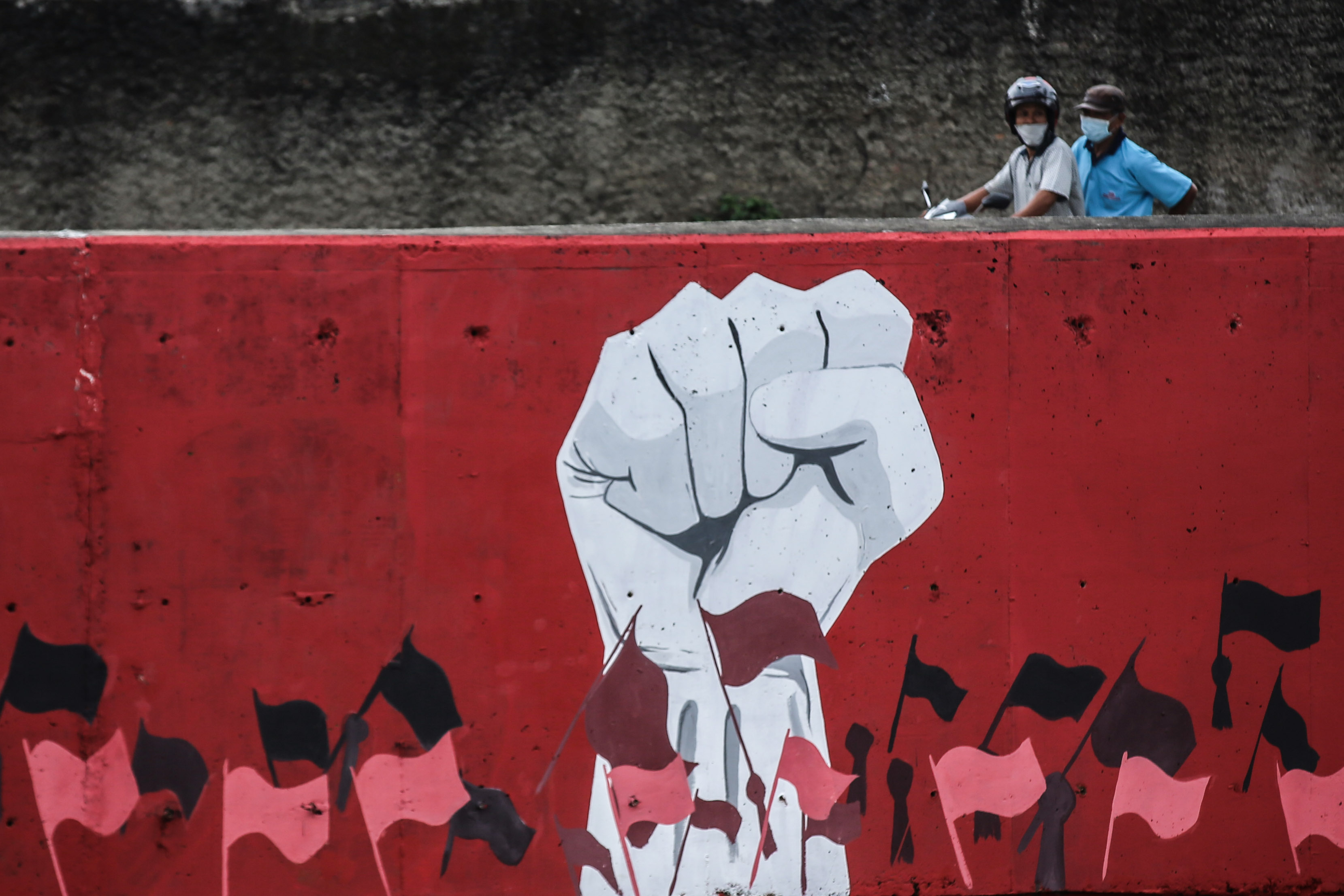 Dengan menggunakan masker, warga melintasi mural terkait Hari Kemerdekaan di wilayah Jakarta