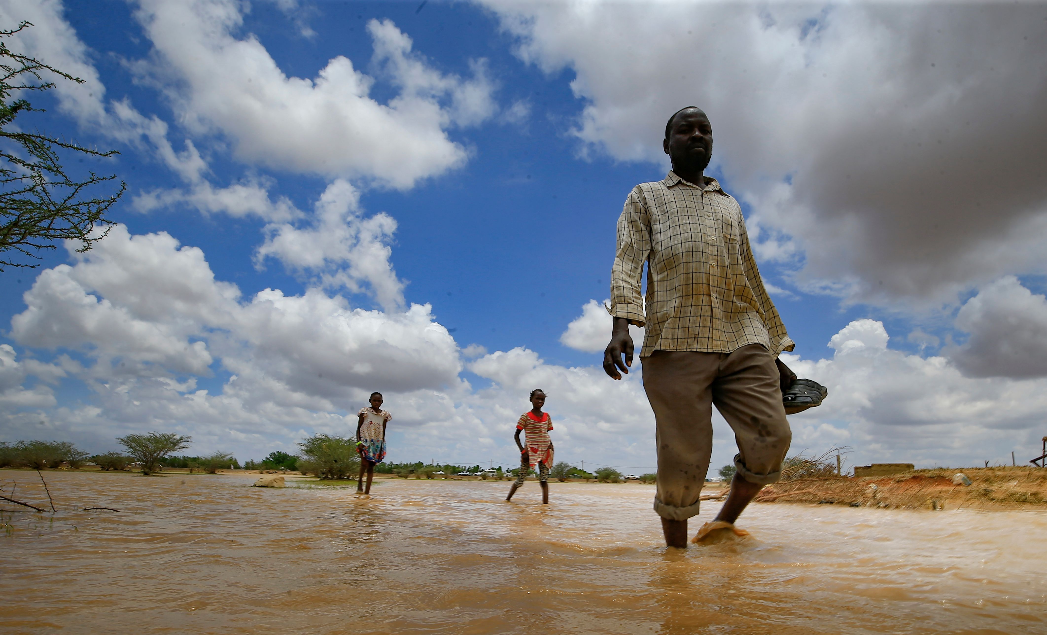 Seorang pria berjalan di jalan yang dilanda banjir di Osaylat, Sudan.