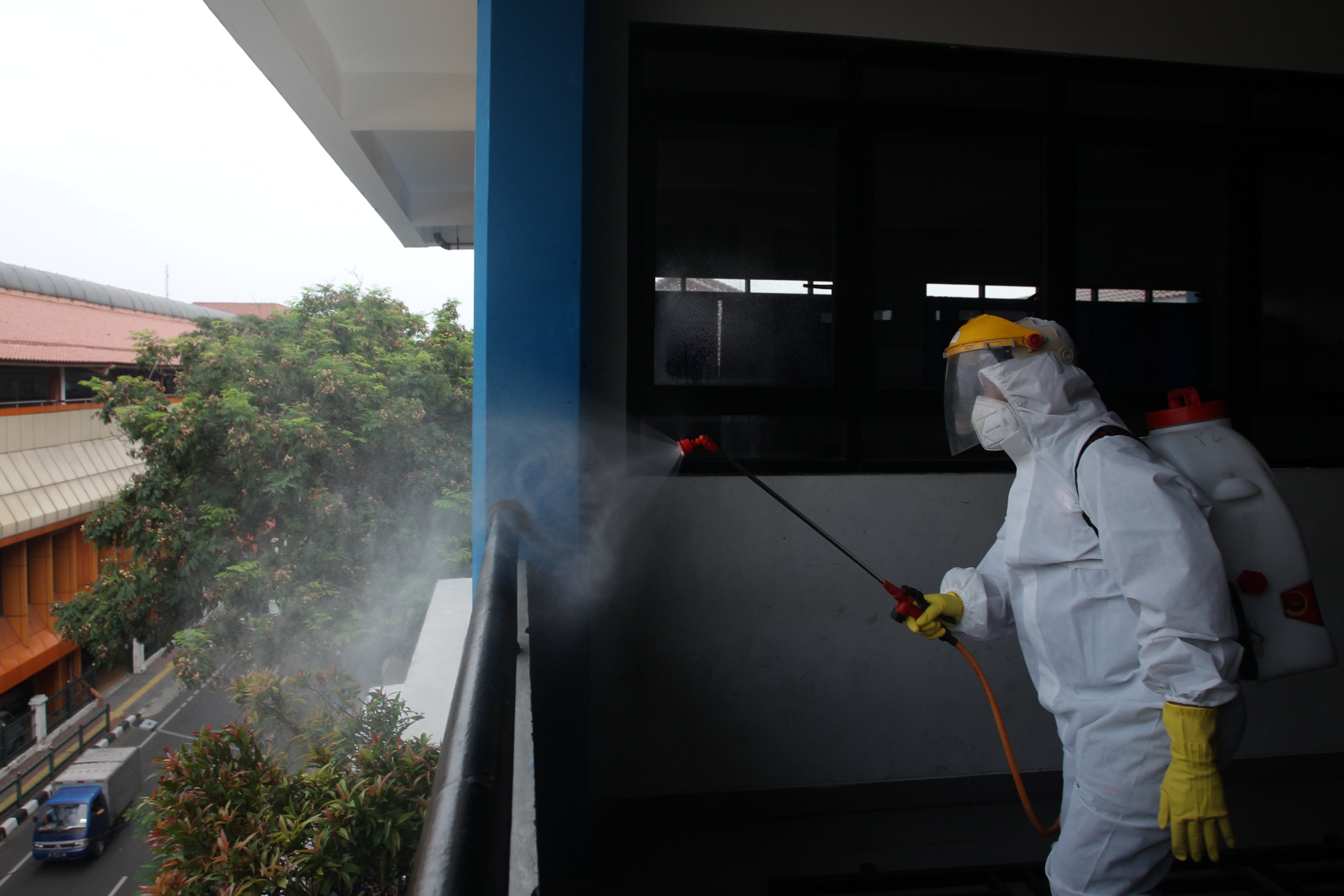 Petugas menyemprotkan disinfektan ke lingkungan sekolah