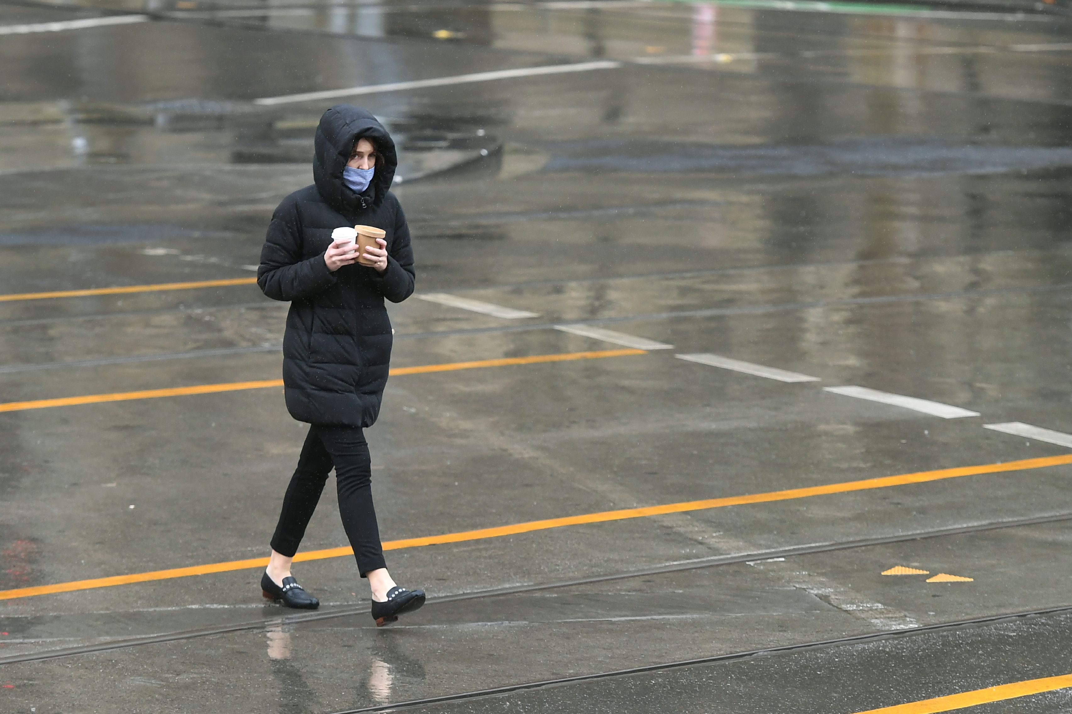 Seorang warga mengenakan masker menyeberang jalan di Melbourne, Australia.