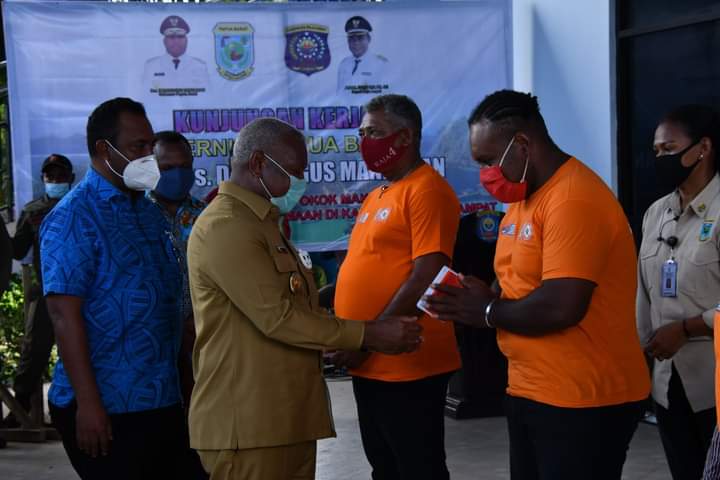 Gubernur Papua Barat Dominggus Mandacan (kedua kiri) menyerahkan bantuan kepada pekerja di Kabupaten Raja Ampat