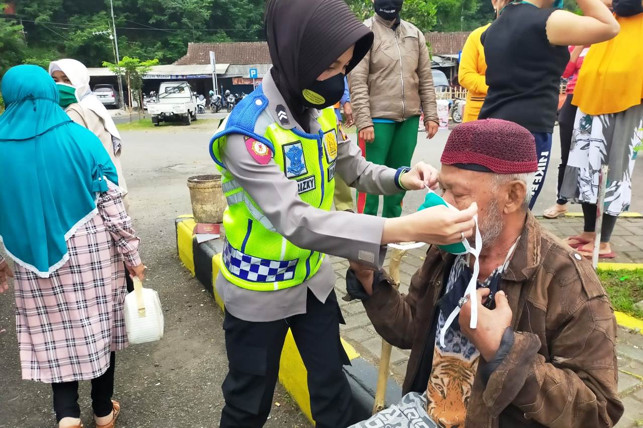 Anggota Polwan Polresta Tasikmalaya memakaikan masker kepada seorang lansia.