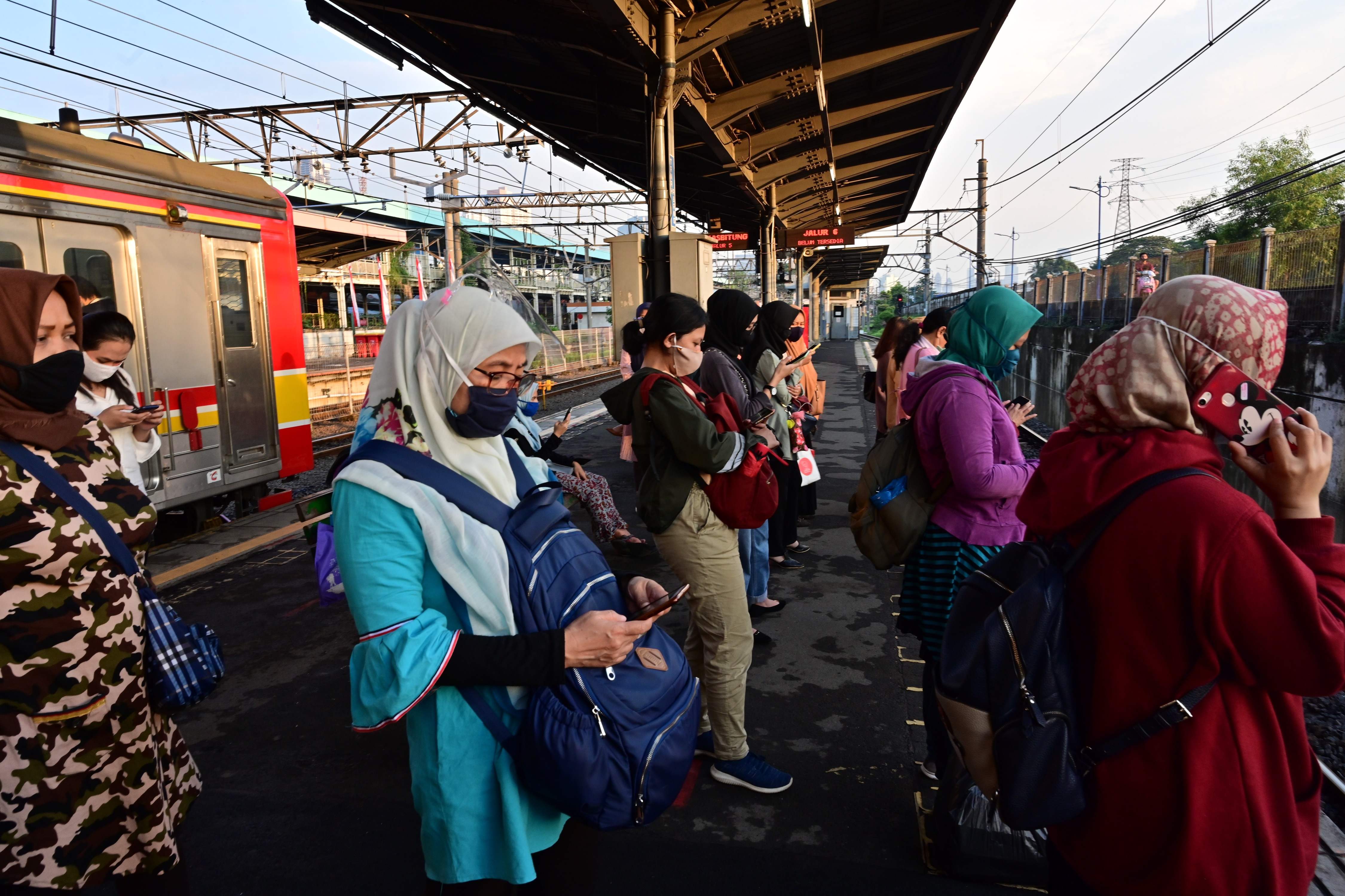 Warga mengenakan masker menunggu kereta di Stasiun Tanah Abang, Jakarta.