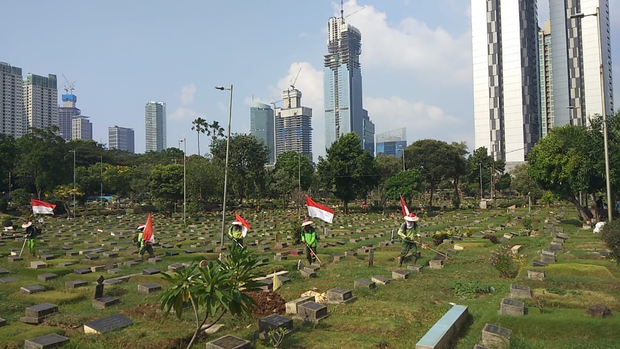 Para petugas di TPU Karet Bivak membawa bendera Merah Putih saat bekerja memotong rumput.