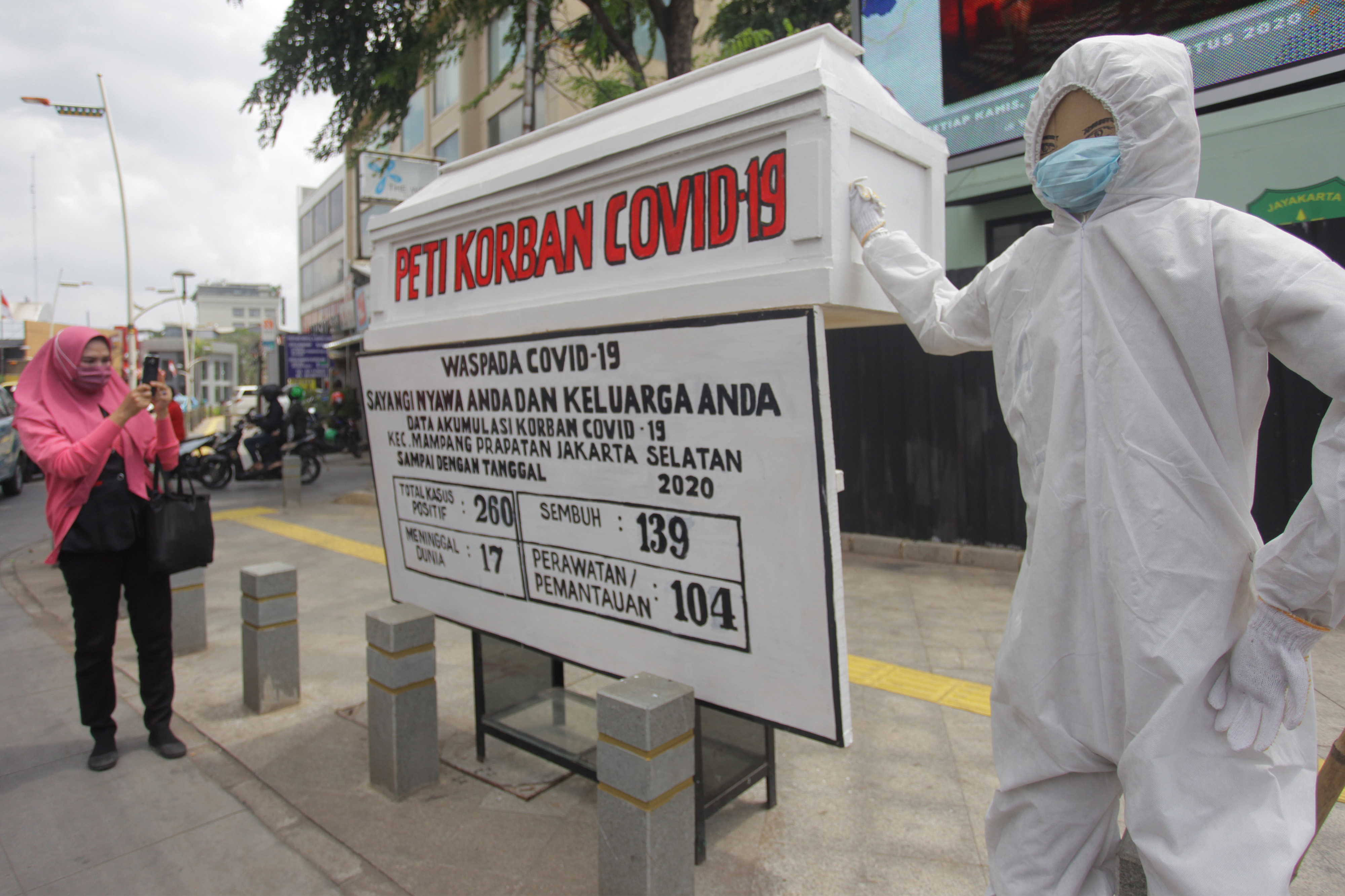 Warga memotret papan informasi tentang jumlah warga terpapar COVID-19 di kawasan Kemang, Jakarta.