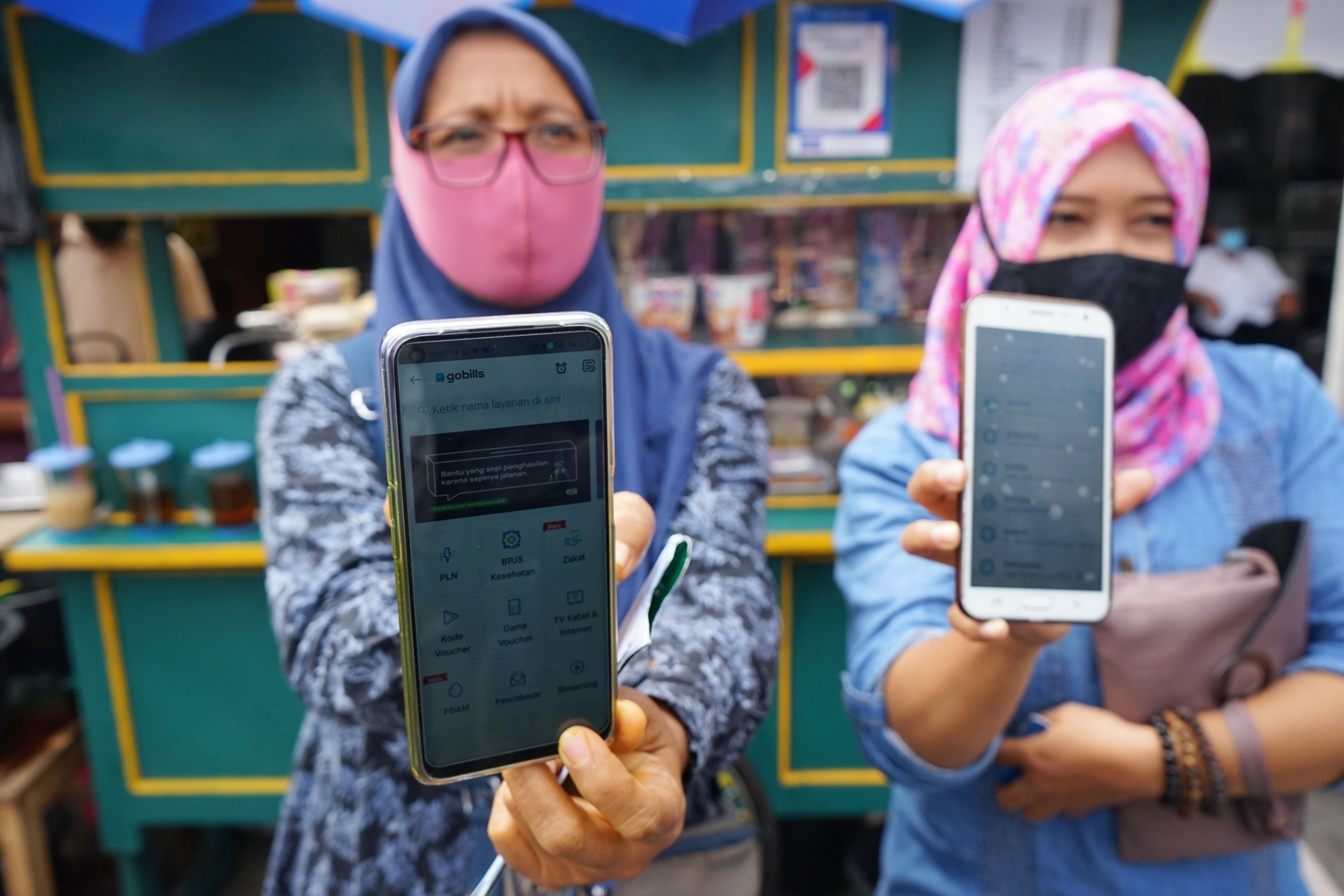 Pedagang menunjukan fitur belanja digital dari ponsel mereka.