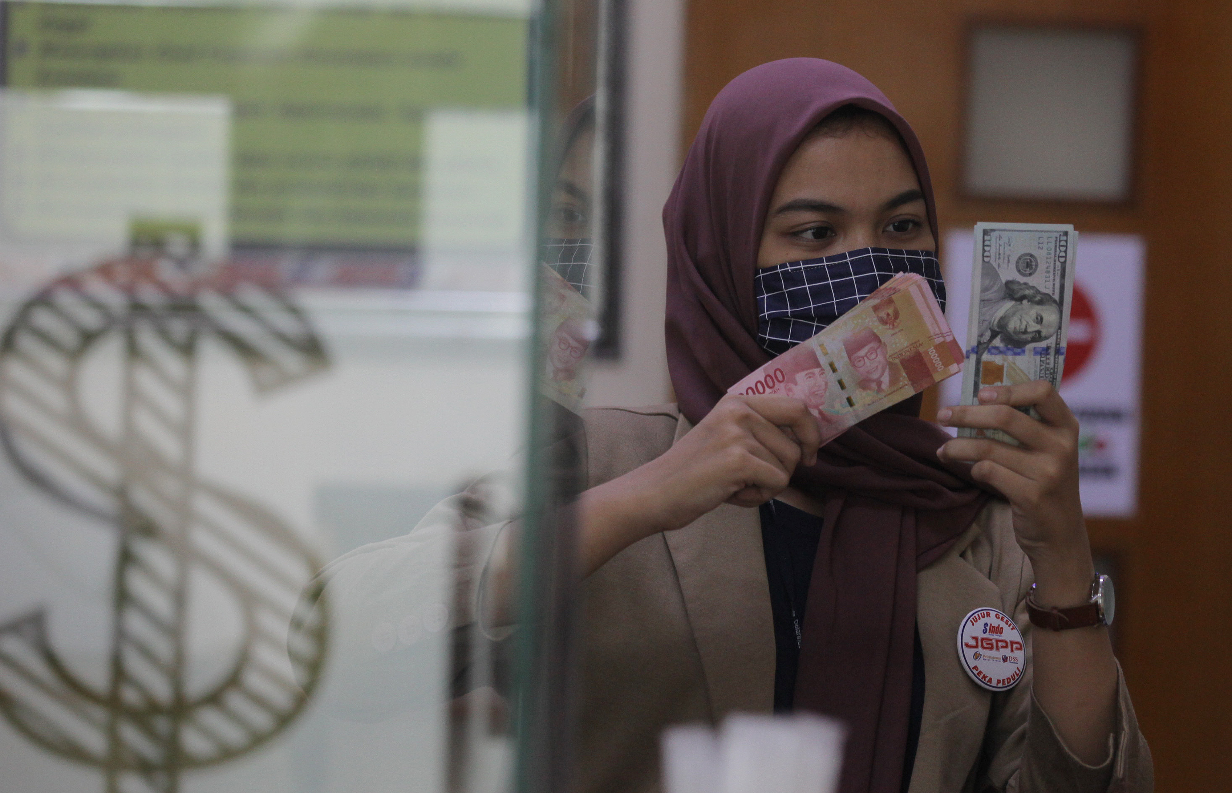 Karyawan gerai penukaran uang menunjukkan rupiah dan dolar AS.