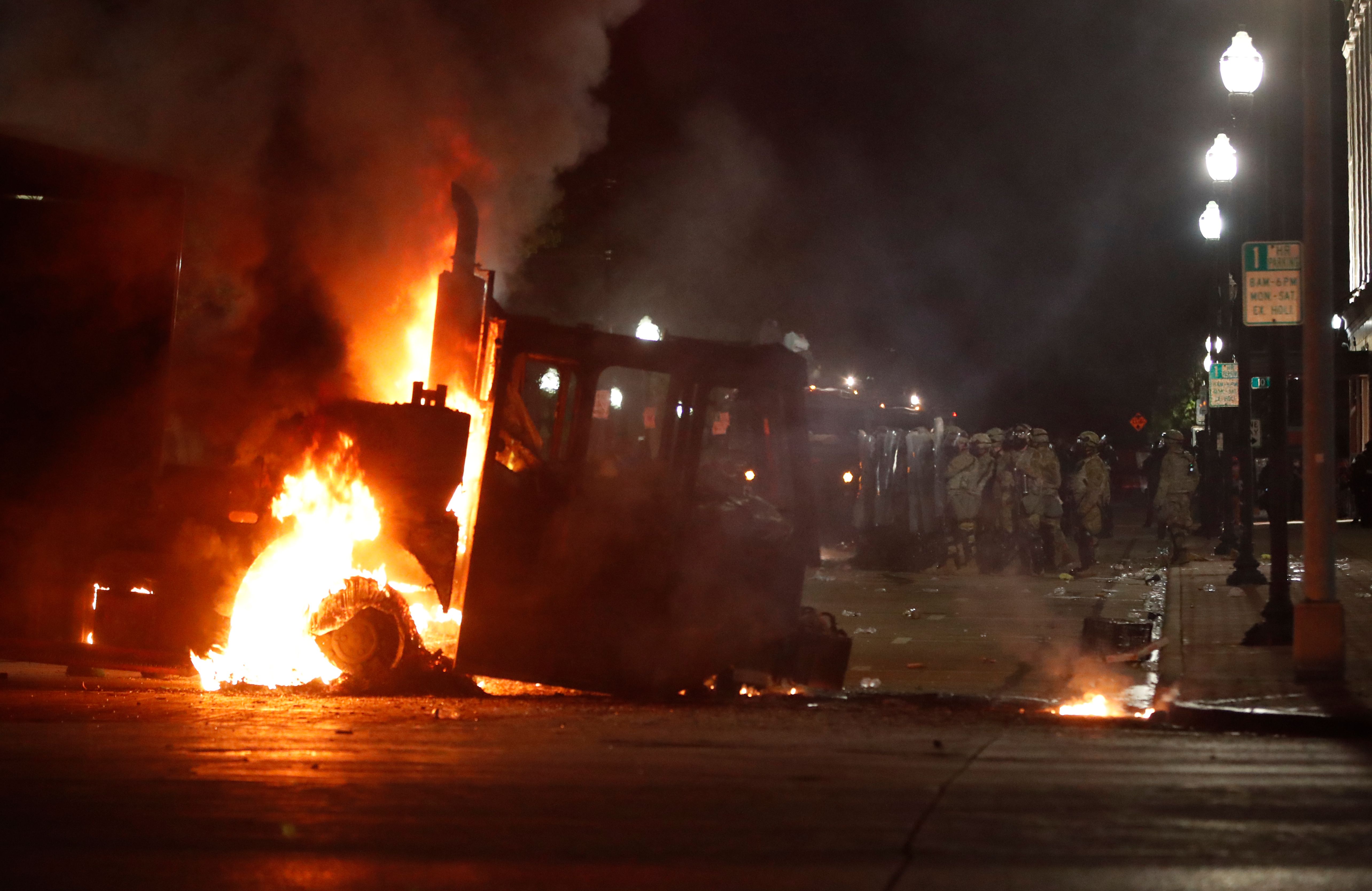 Polisi Kenoshamembentuk barisan di belakang truk yang terbakar selama demonstrasi menentang penembakan Jacob Blake di Kenosha, Wisconsin 