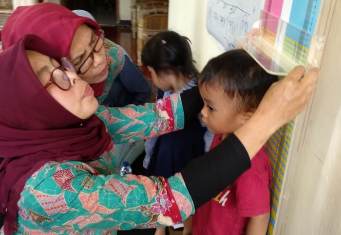 Tim pengabdian masyarakat FKM UI sedang mendeteksi stunting pada anak. 
