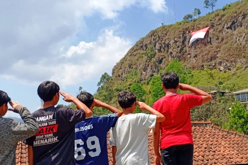 Sejumlah anak menghormat bendera Merah Putih saat kenaikan bendera di tebing Gunung Batu Lembang, Kabupaten Bandung Barat, Minggu (16/8).