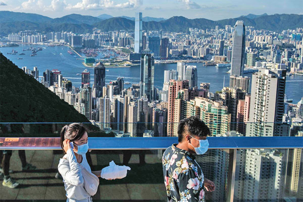 EKONOMI HONG KONG: Pengunjung melintas di kawasan Victoria Peak dengan latar belakang gedung perkantoran dan kawasan komersial  