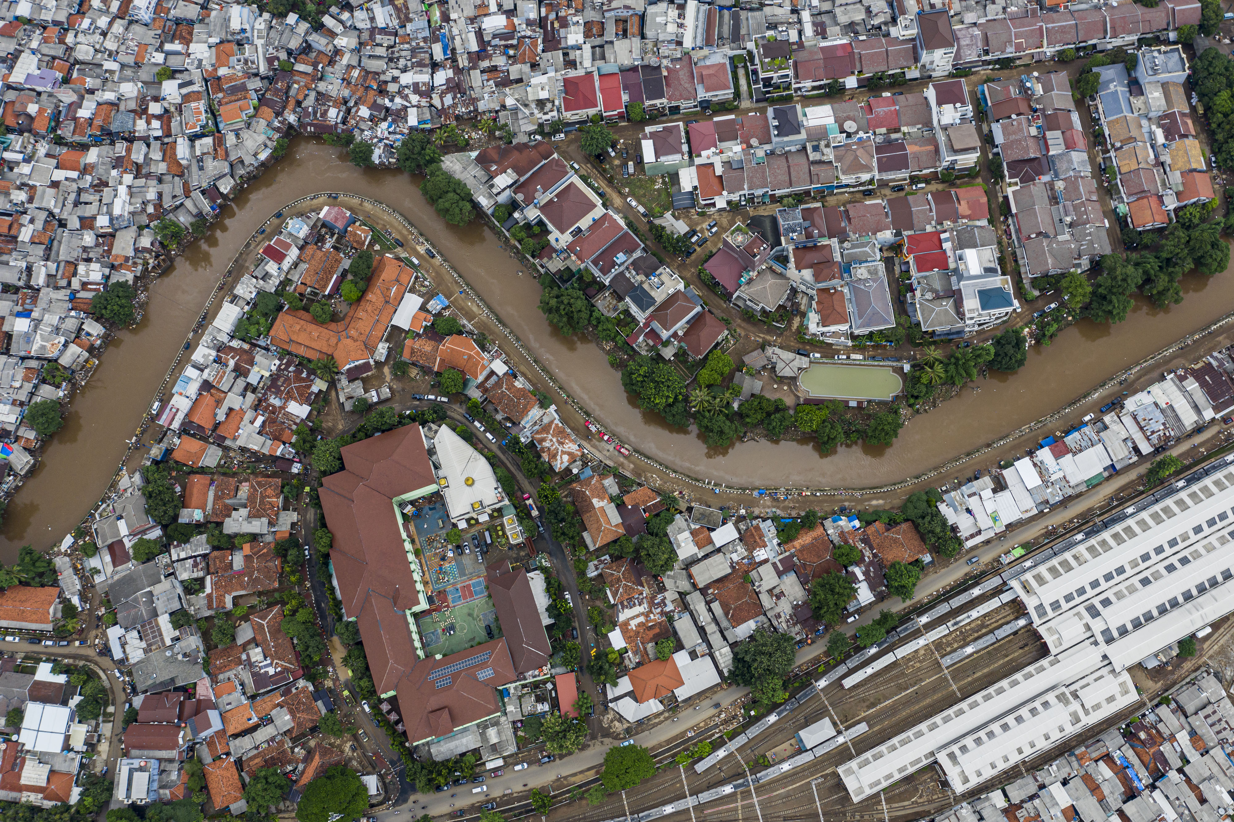 Foto udara suasana wilayah bantaran sungai Ciliwung yang belum dinormalisasi dan yang sudah dinormalisasi di kawasan Bukit Duri