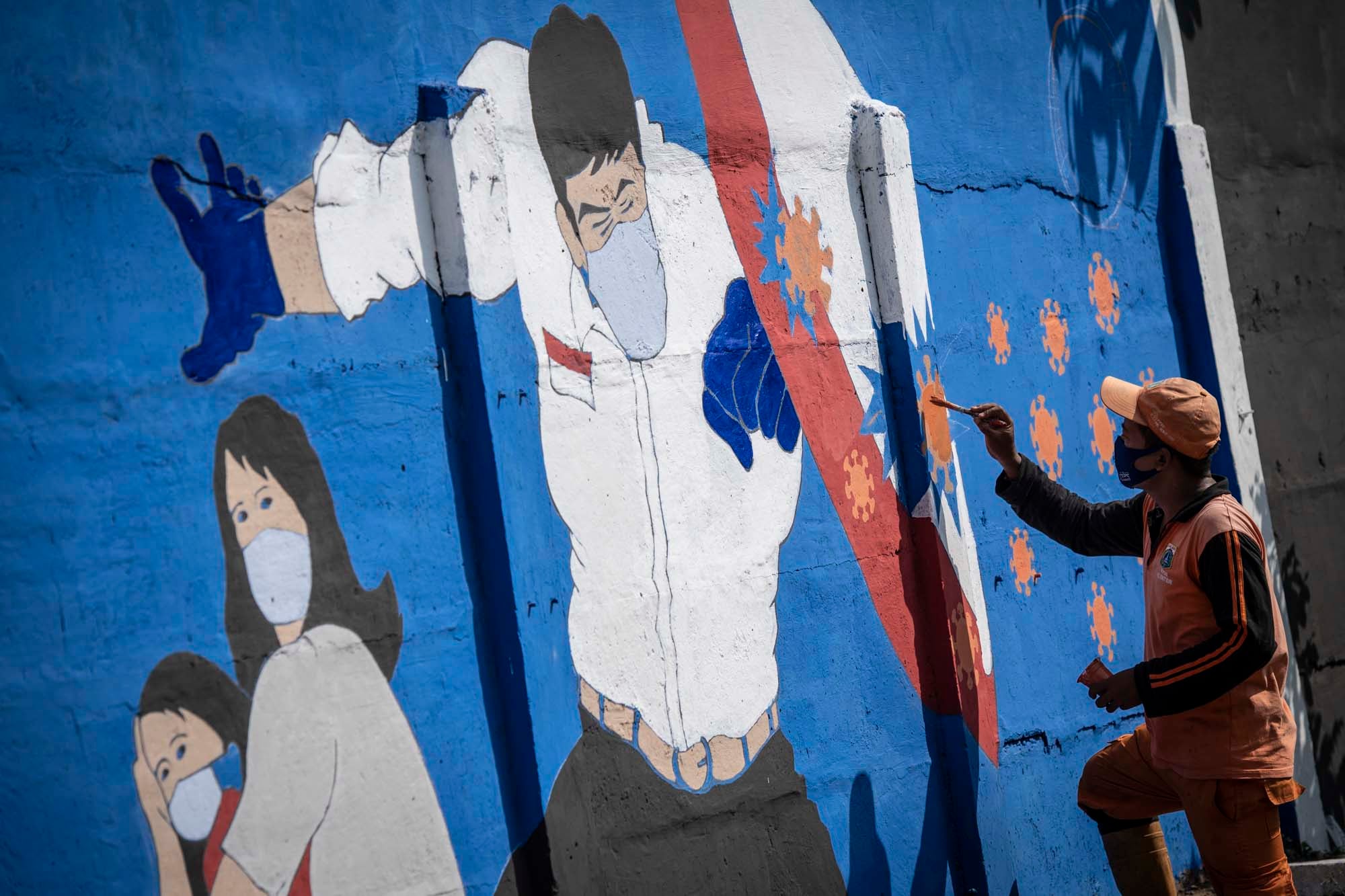 Petugas PPSU menyelesaikan pembuatan mural covid-19 di kawasan Tebet, Jakarta.