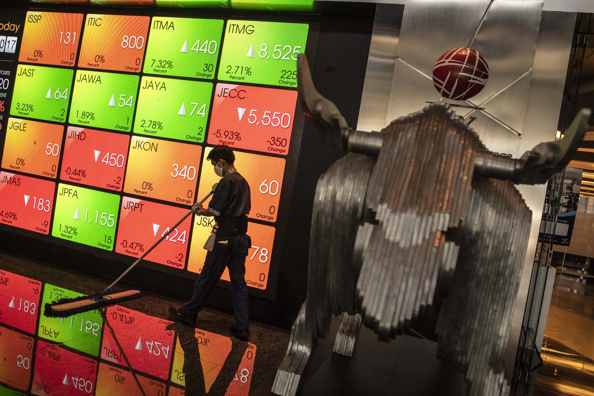 Pekerja membersihkan lantai dekat layar pergerakan saham di gedung BEI.