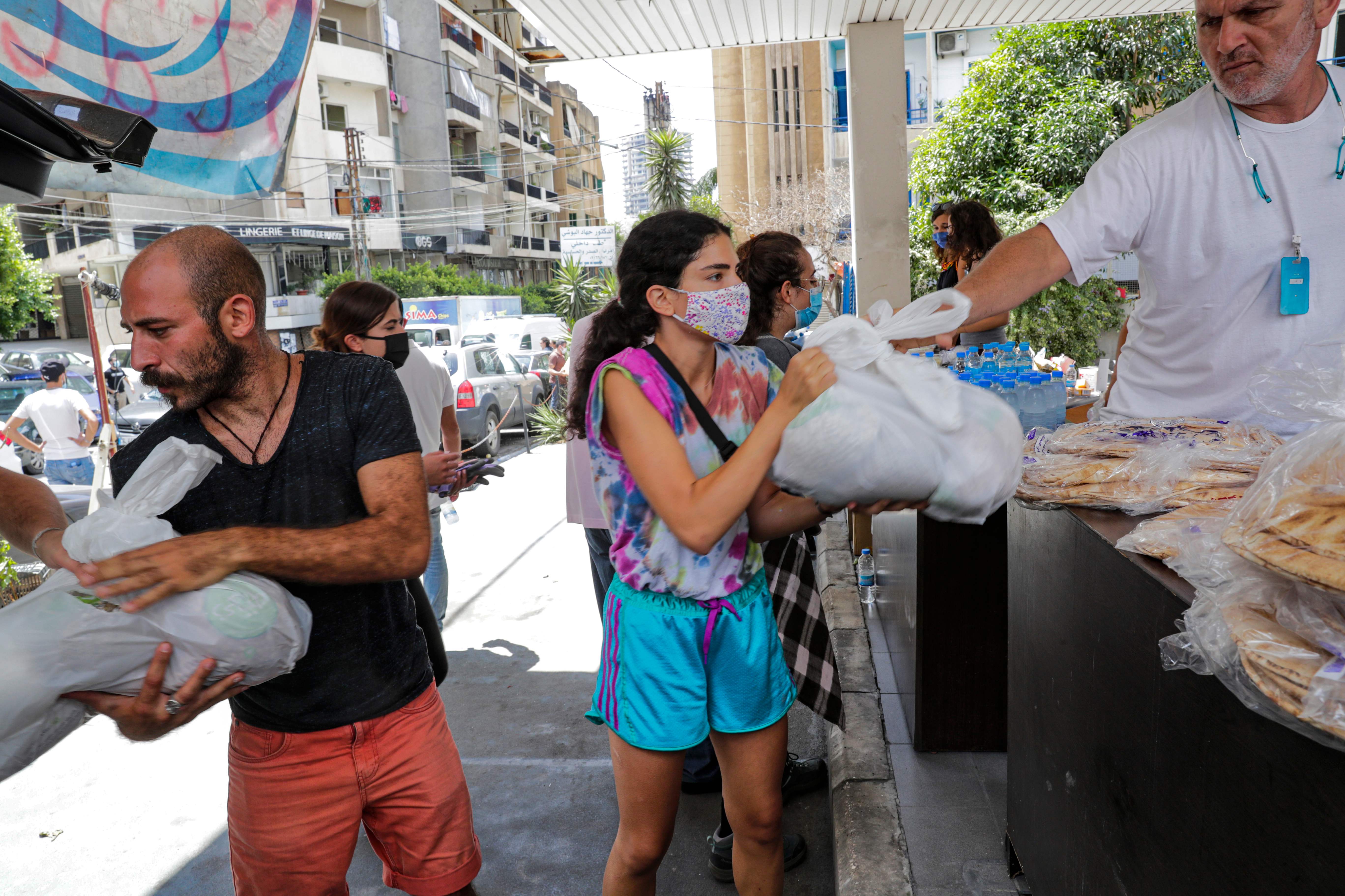 Relawan yang mengenakan masker membagikan makanan kepada korban ledakan Beirut, Libanon.