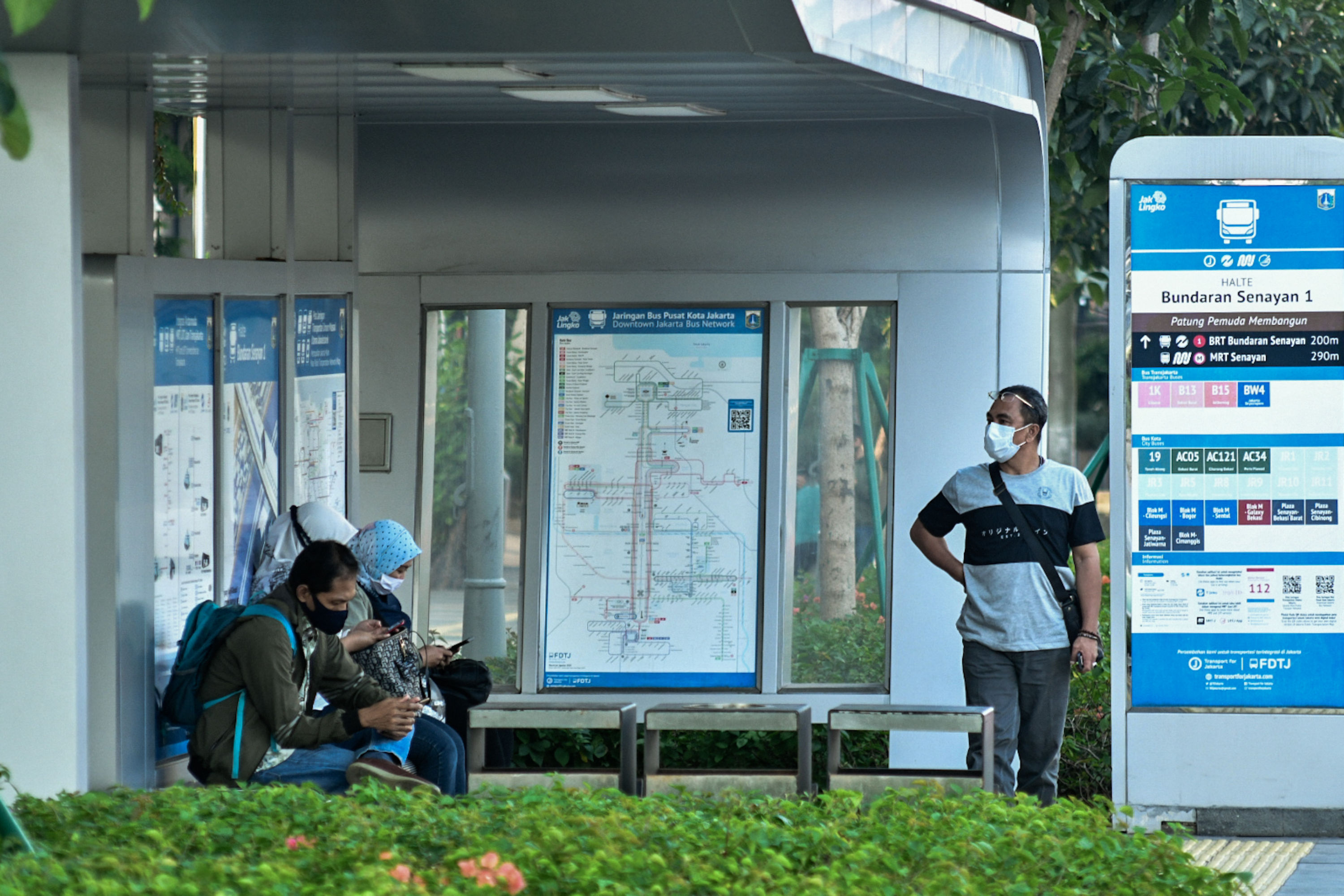 Warga mengenakan masker saat menunggu kedatangan bus di halte bus kawasan Senayan, Jakarta, Sabtu (1/8/2020). 