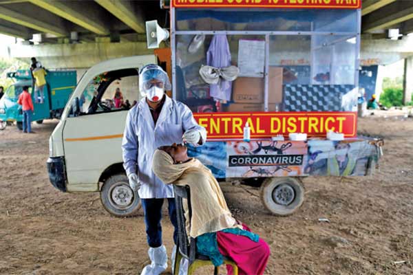 Tenaga medis mengenakan alat pelindung diri (APD) mengambil sampel swab untuk pengujian covid-19 di New Delhi, India