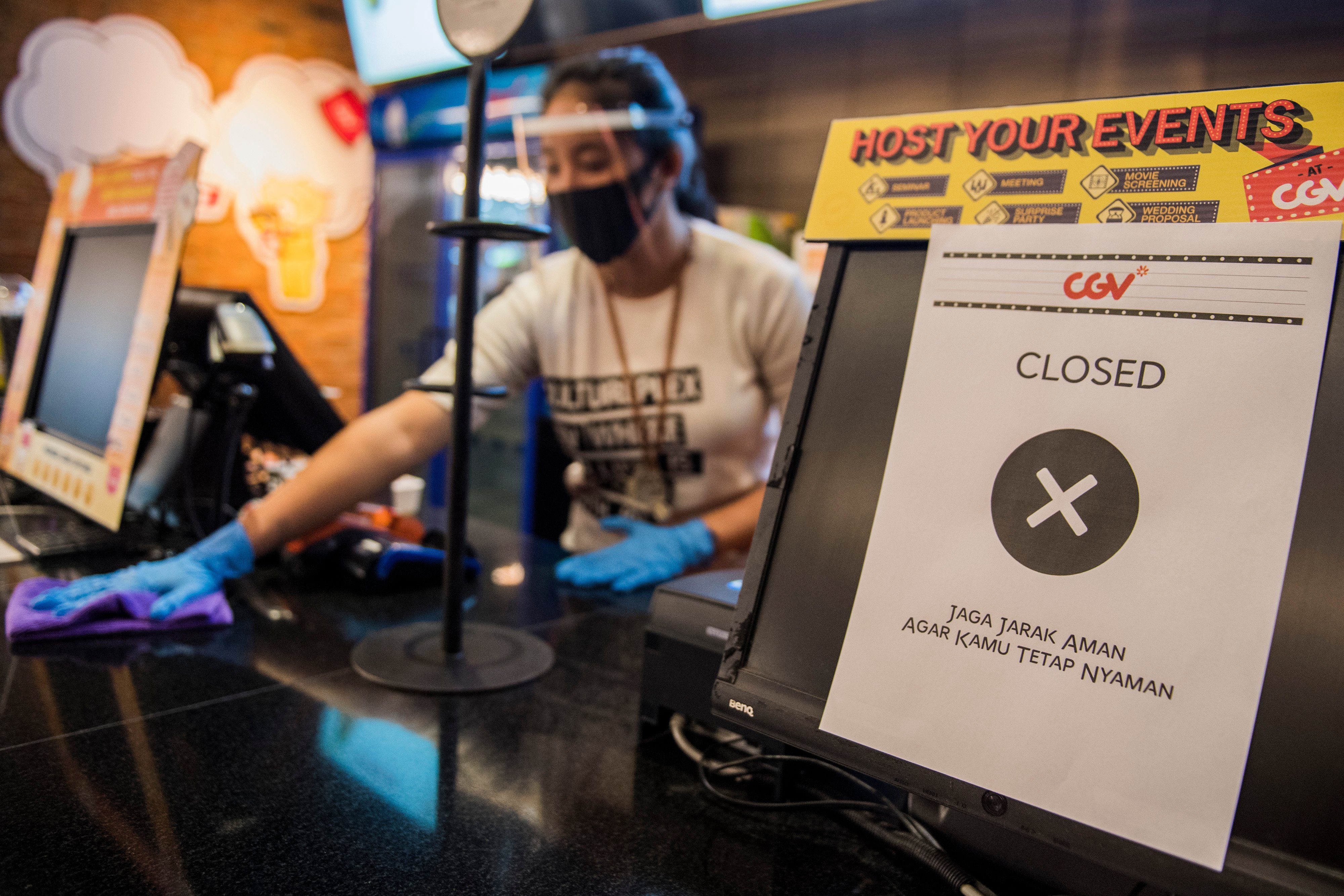Pekerja membersihkan meja dengan penerapan protokol kesehatan saat simulasi pembukaan dan peninjauan tempat hiburan bioskop CGV