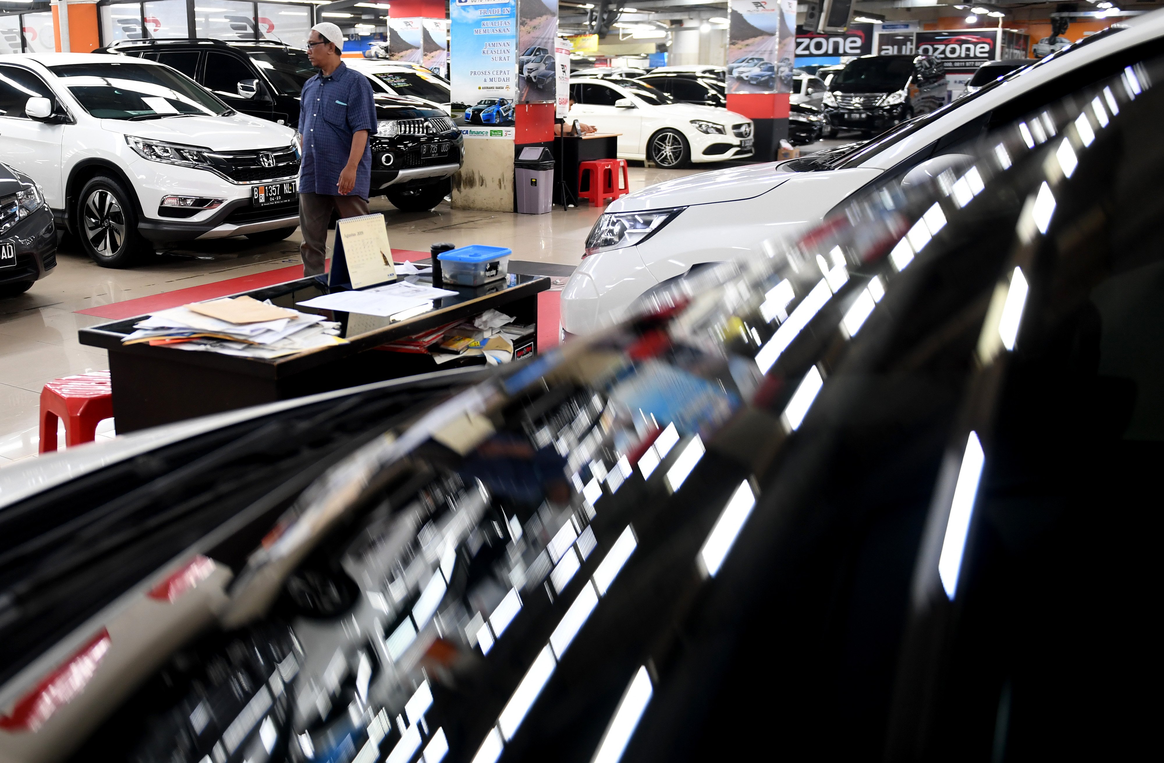 Calon pembeli berjalan melintasi deretan mobil bekas yang dijual di bursa mobil bekas, WTC Mangga Dua, Jakarta, Jumat (9/8/2019).