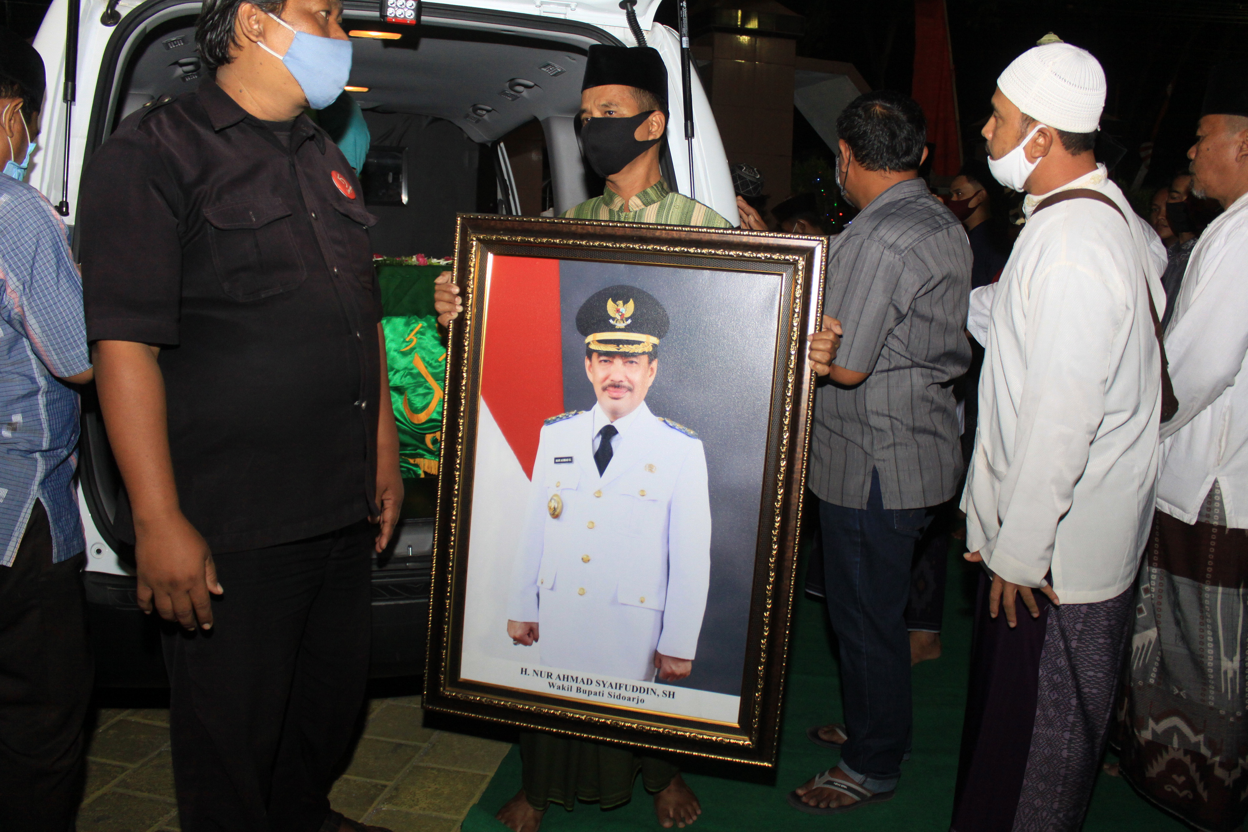 Keluarga membawa foto almarhum Plt Bupati Sidoarjo Nur Ahmad Syaifuddin saat tiba di rumah duka, kawasan Janti, Waru, Sidoarjo, Jawa Timur. 