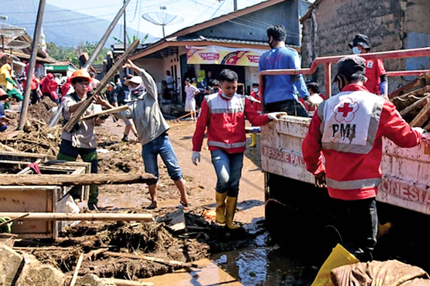 BANTU EVAKUASI: Relawan Palang Merah Indonesia (PMI) membantu warga membersihkan puing- puing dan material banjir di Kampung Cibuntu,  