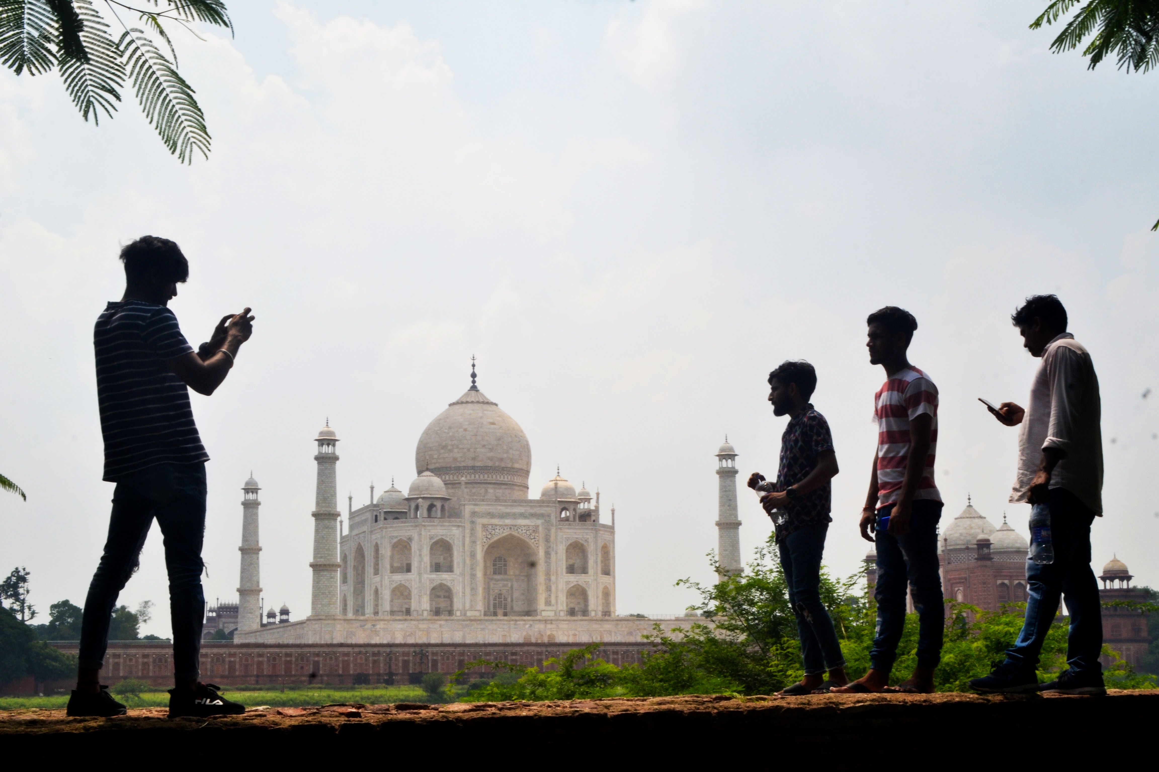 Pengujung berfoto dengan latar belakang Taj Mahal di Agra, India.