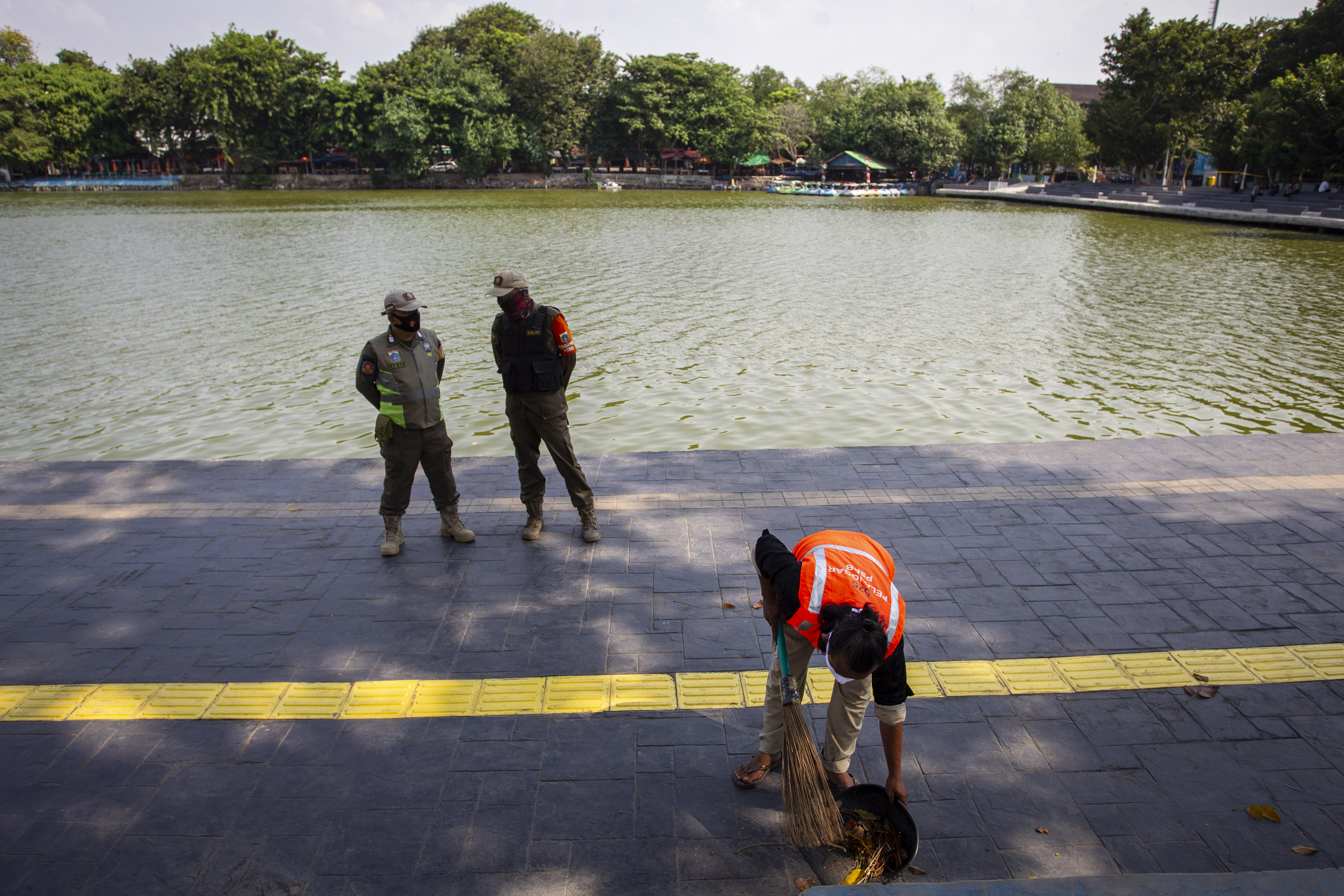 Warga pelanggar protokol kesehatan menyapu jalan usai mengikuti sidang Operasi Yustisi di kawasan Danau Sunter, Jakarta.