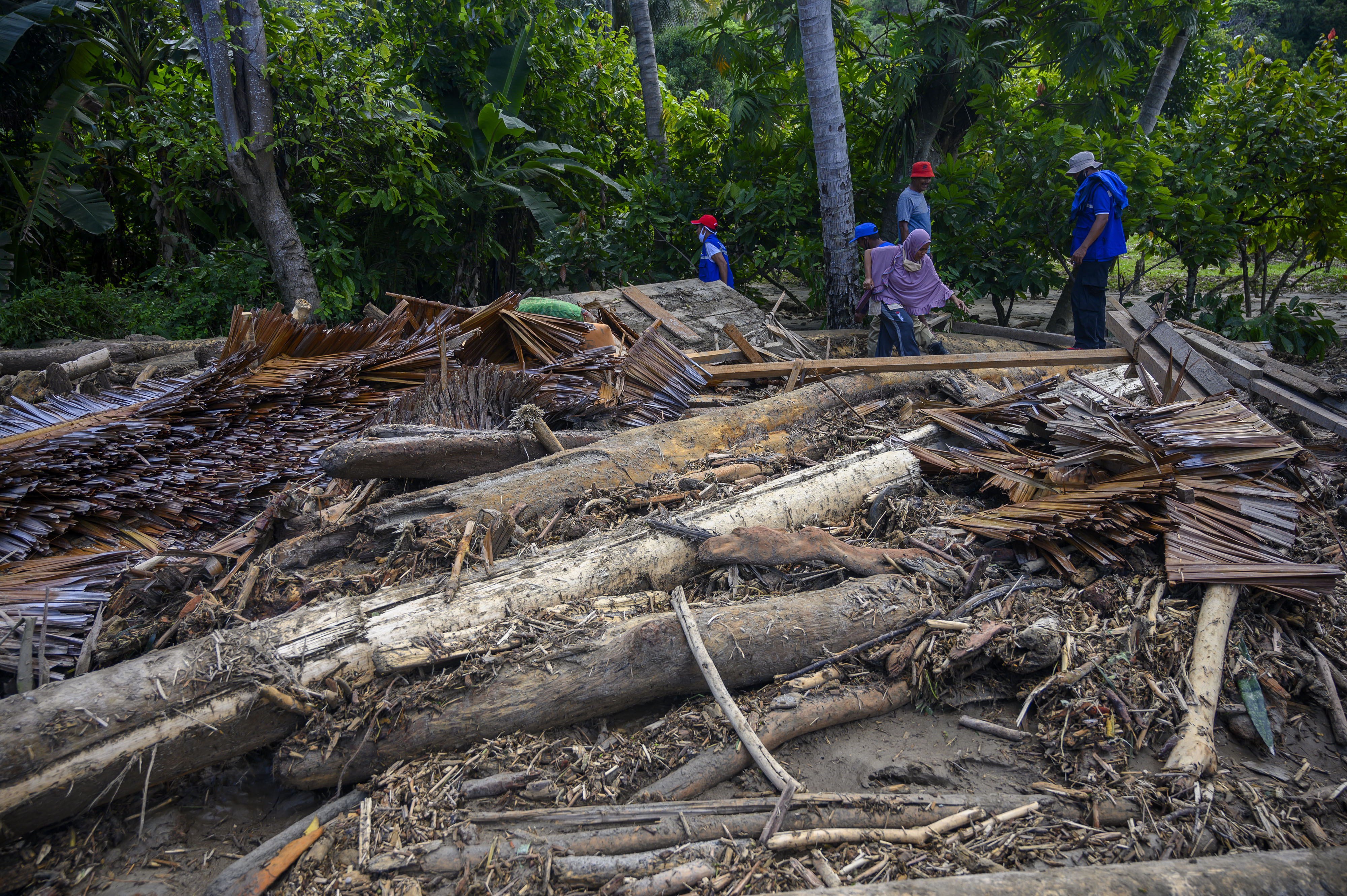 Warga melintas di dekat puing rumah yang hancur akibat diterjang banjir di Desa Oloboju, Kabupaten Sigi, Sulawesi Tengah. 11 Juli lalu.