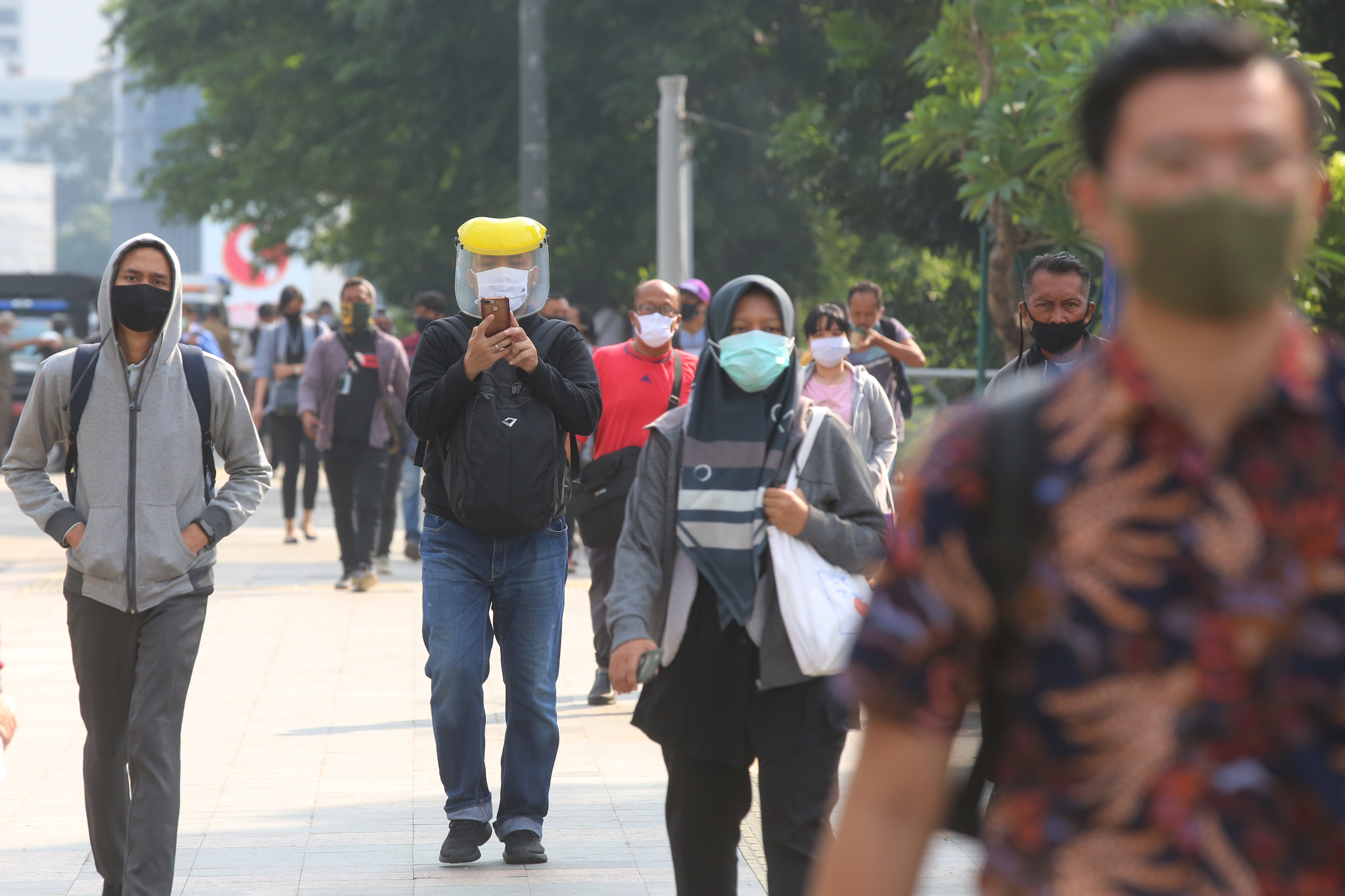 Sejumlah pekerja melintasi trotoar kawasan Sudirman, Jakarta.