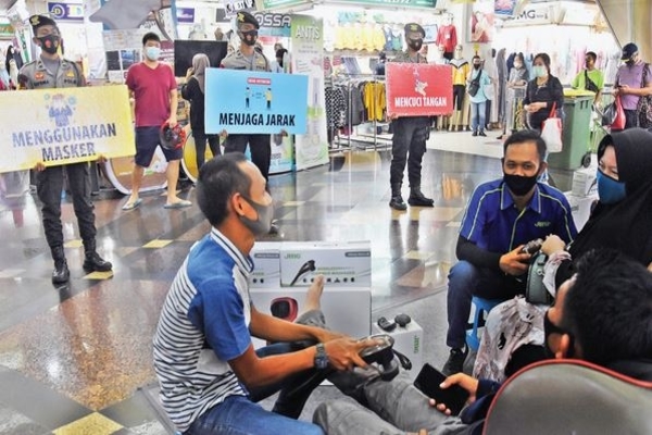 Polisi memegang poster imbauan saat menggelar kampanye penegakan protokol kesehatan di Blok A Pasar Tanah Abang, Jakarta Pusat, kemarin.