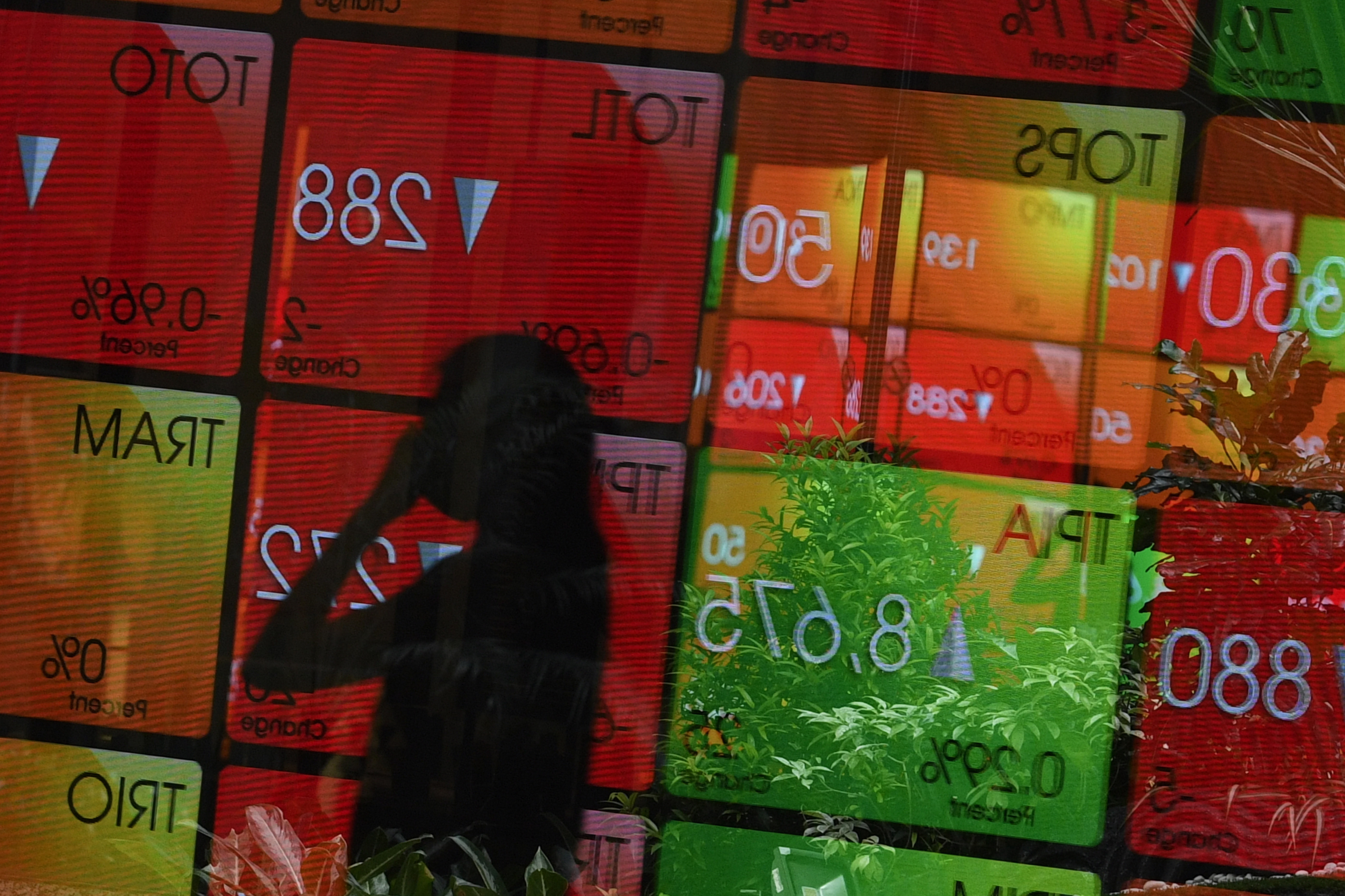 Pejalan melintas di depan monitor perdagangan saham di Bursa Efek Indonesia.