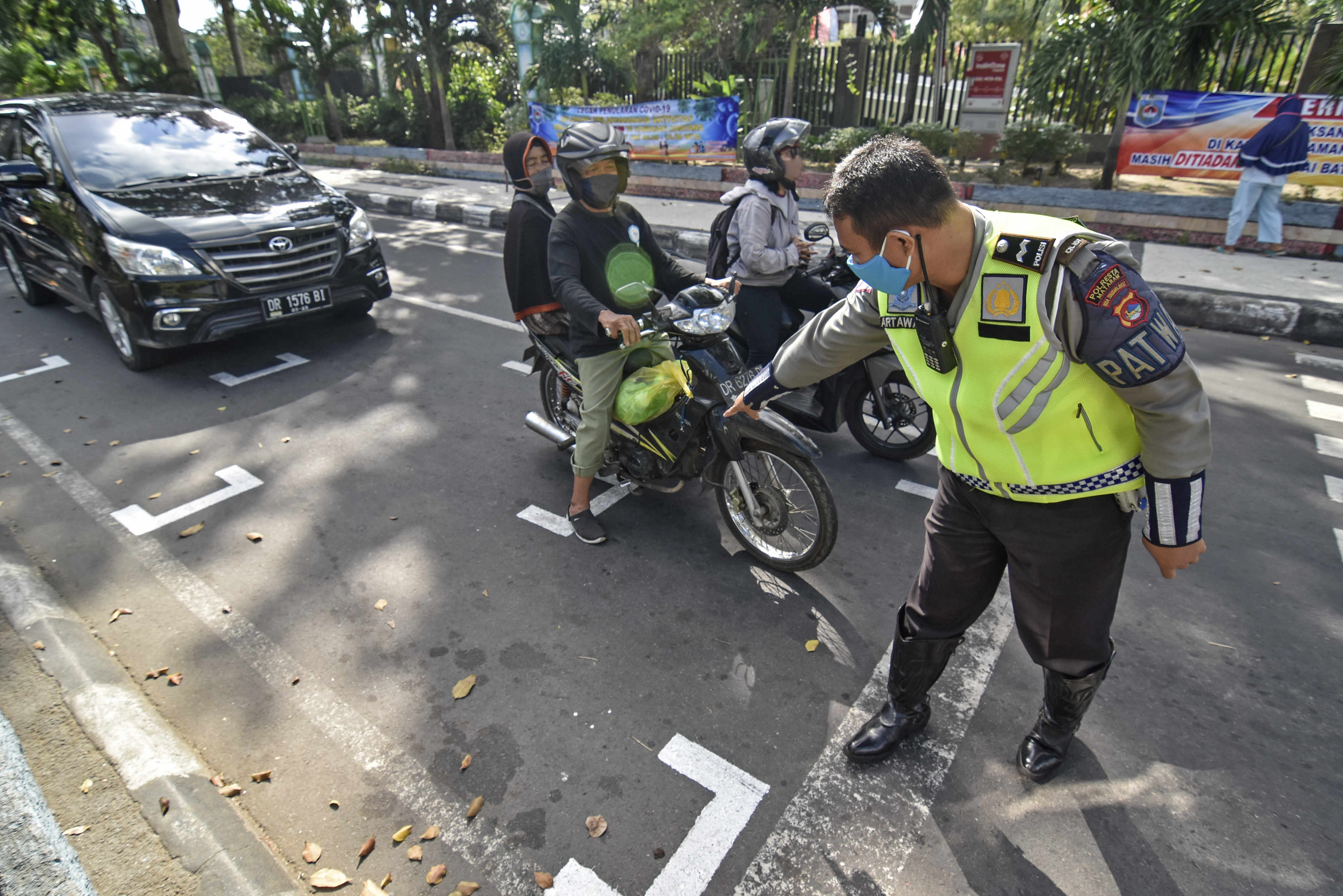 Polantas menunjukkan marka yang dibuat secara berjarak kepada pengendara sepeda motor saat berhenti di perempatan BI Mataram, NTB