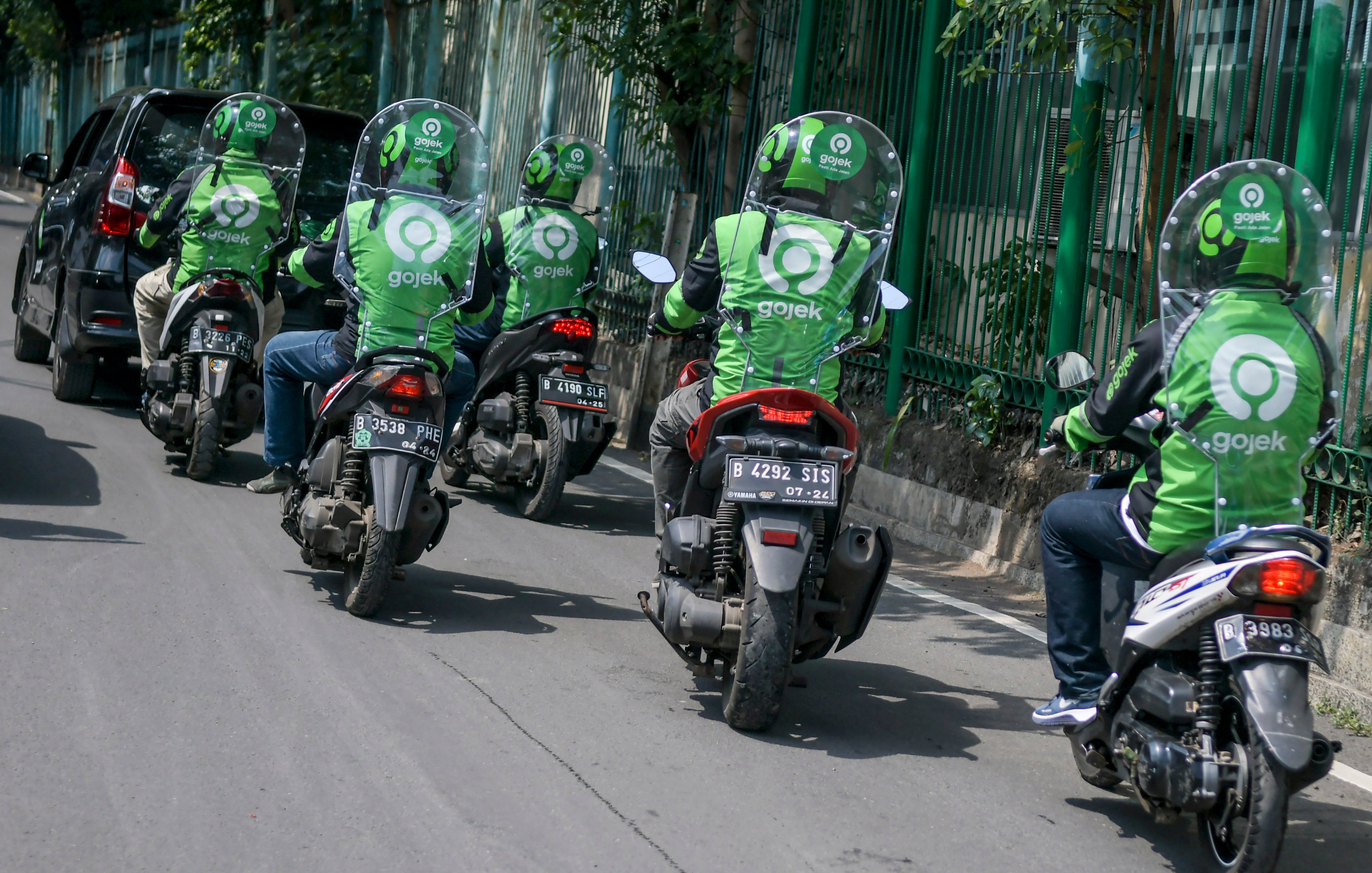 engemudi ojek daring mengenakan sekat pelindung saat melintas di kawasan jalan Kendal, Jakarta.