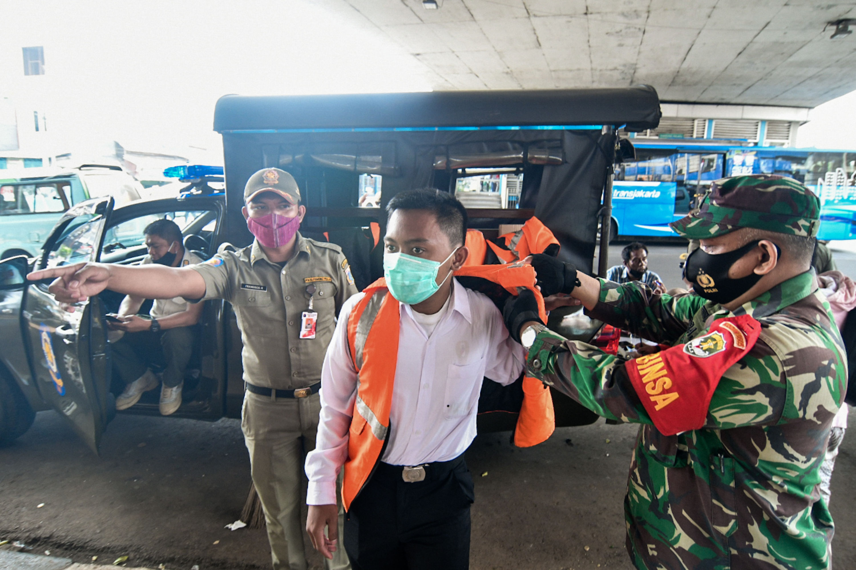 Warga yang terjaring razia masker dikenakan sanksi sosial di Kawasan Kampung Melayu, Jakarta.