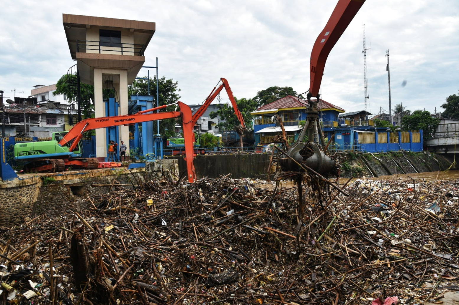 Petugas menggunakan alat berat membersihkan sampah yang menumpuk di Pintu Air Manggarai, Jakarta, Selasa (22/9).