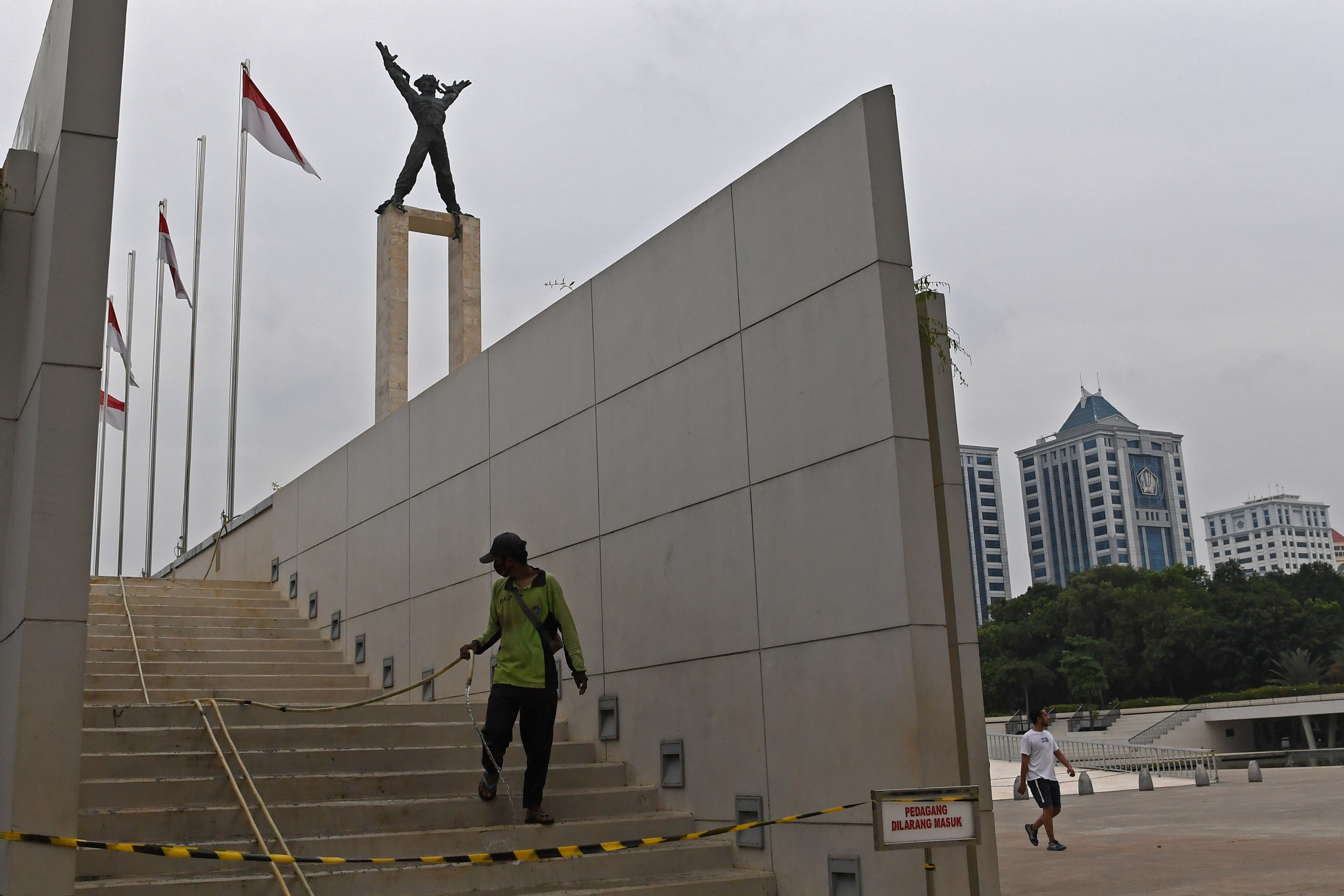 Petugas kebersihan menyiram kawasan lapangan Banteng di Jakarta yang ditutup lagi untuk umum sejak Senin (14/9).