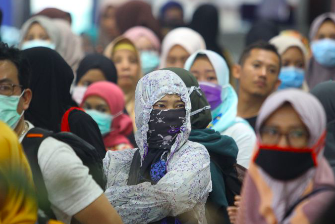 Calon penumpang mengenakan masker di Stasiun Pasar Turi, Surabaya, Jawa Timur, Minggu (15/3).