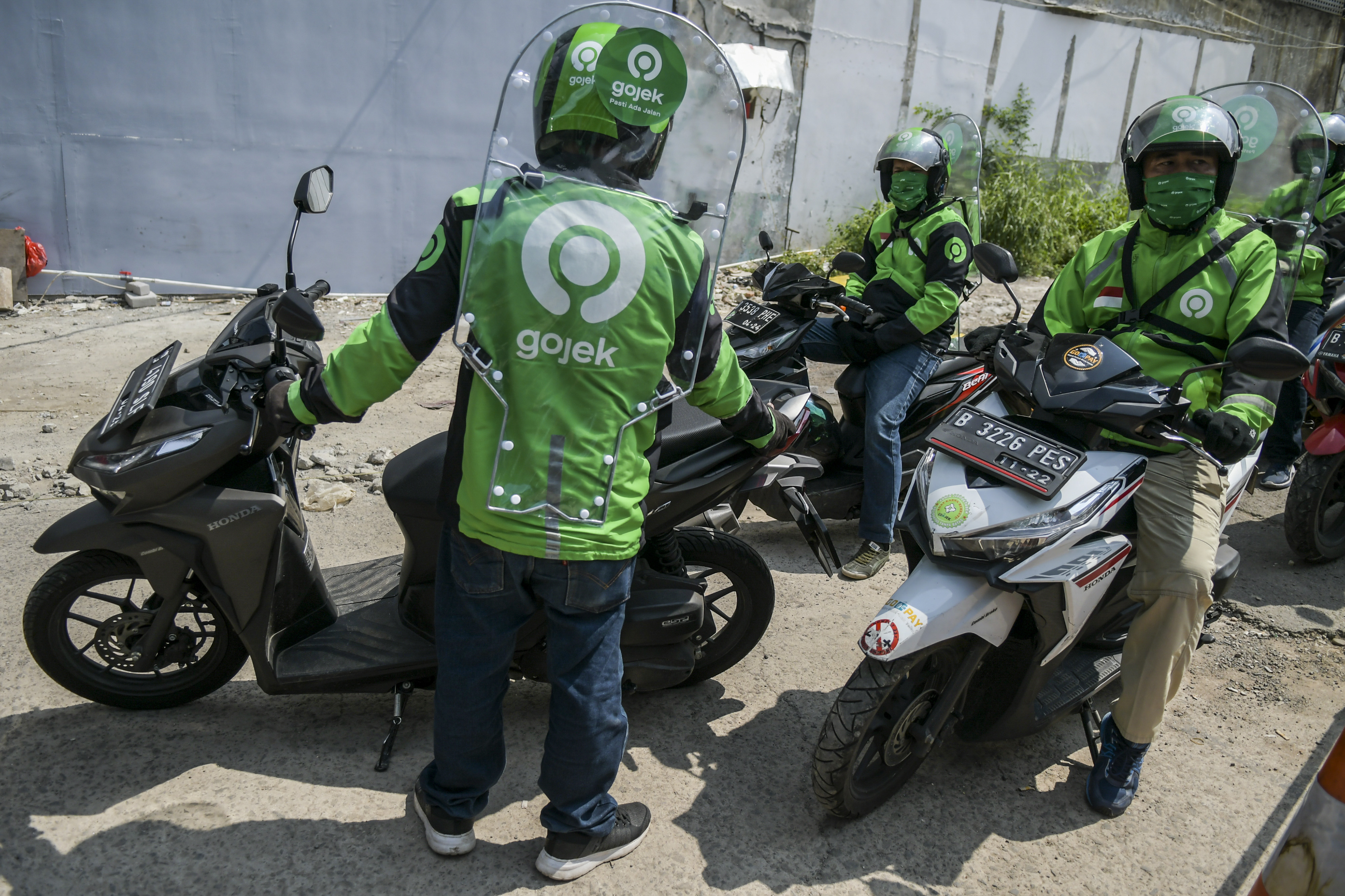  Pengemudi ojek daring mengenakan sekat pelindung saat menunggu penumpang di kawasan jalan Kendal, Jakarta.