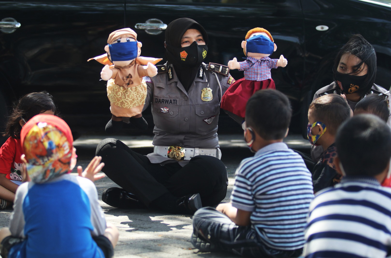 Seorang Polwan memainkan boneka bermasker di Kediri Jawa Timur untuk mengajarkan anak-anak soal protokol kesehatan.