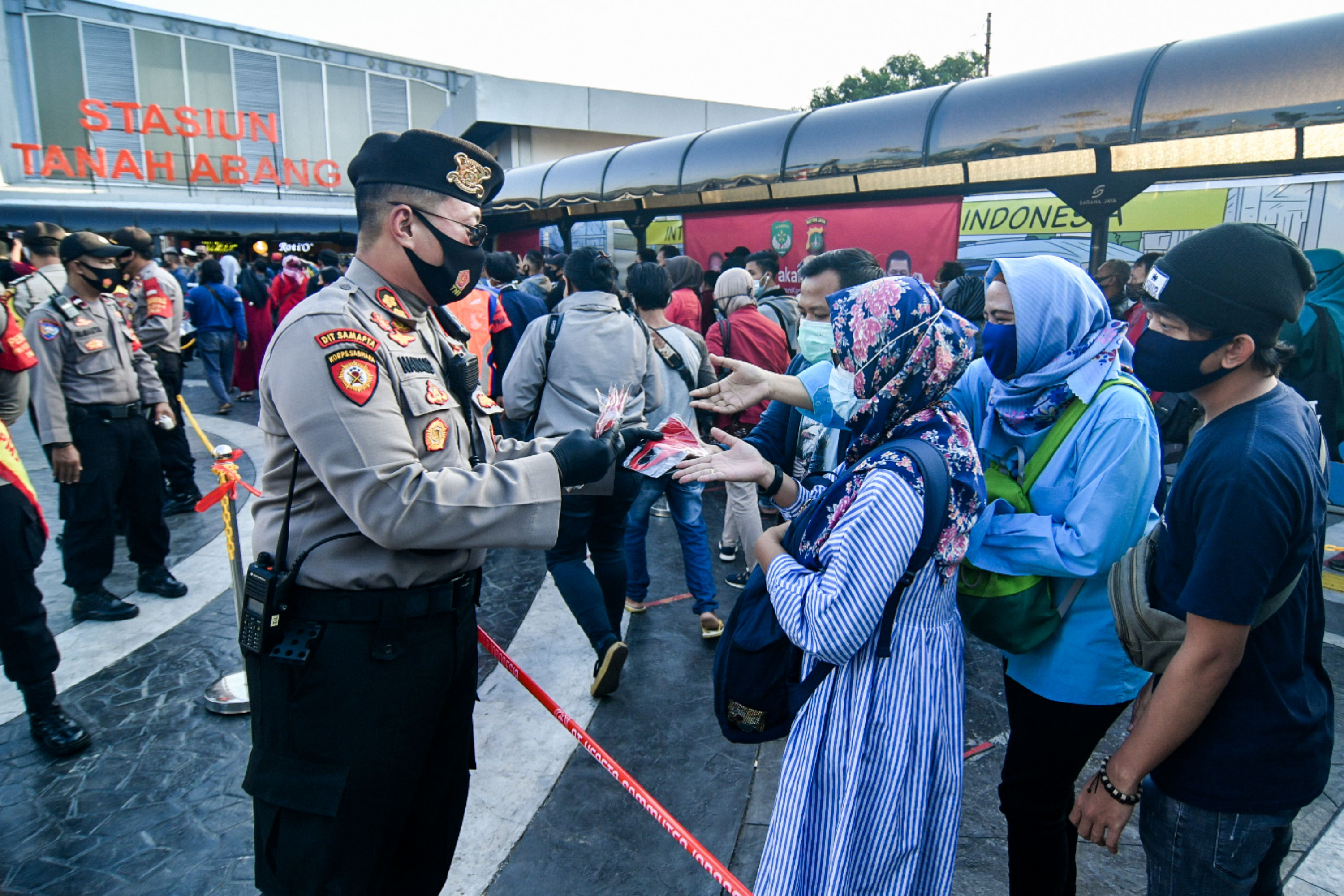 Anggota Polisi membagikan masker untuk calon penumpang KRL Commuterline di Stasiun Tanah Abang, Jakarta, Kamis (27/8).